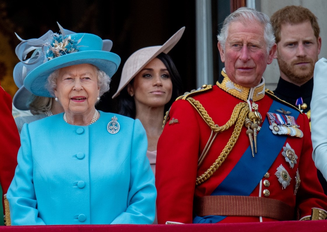 Queen Elizabeth II, Prince Charles, Prince Harry, and Meghan Markle standing on Buckingham Palace balcony during Trooping the Colour.