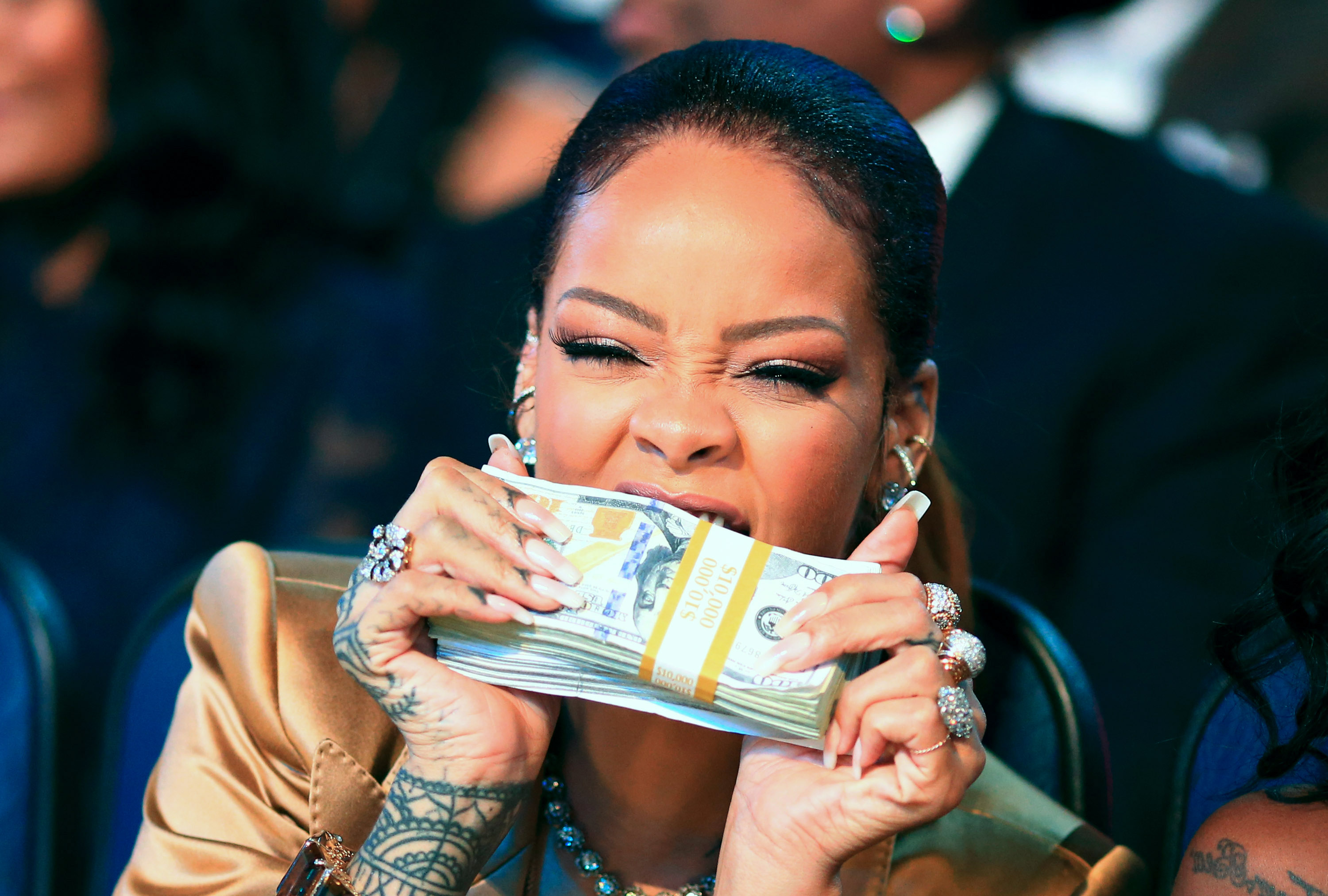 Recent billionaire Rihanna poses with a stack of money. 
