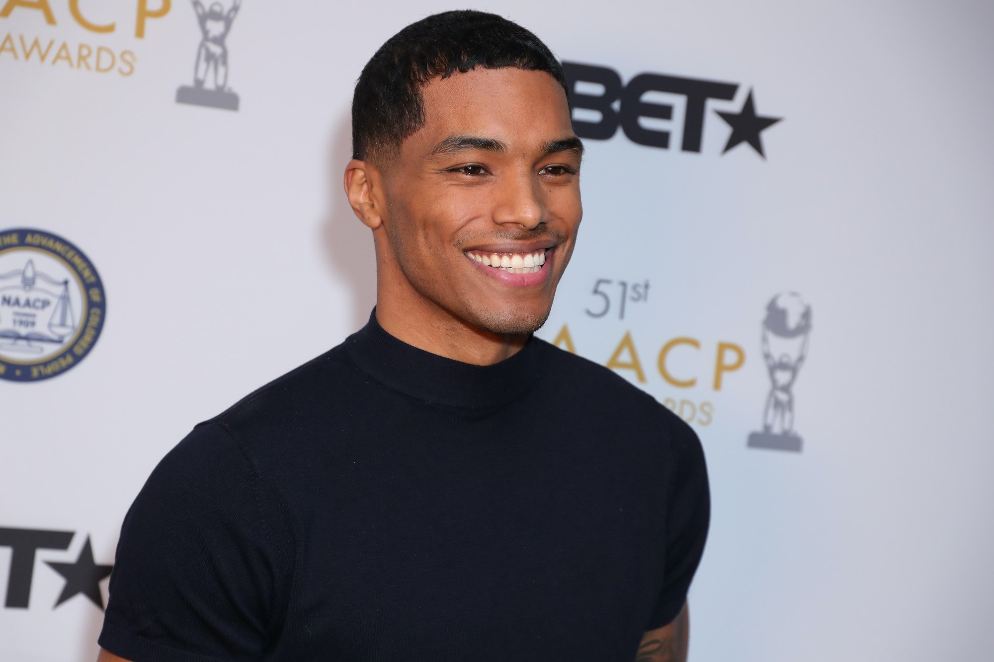 Rome Flynn smiling in front of a white background