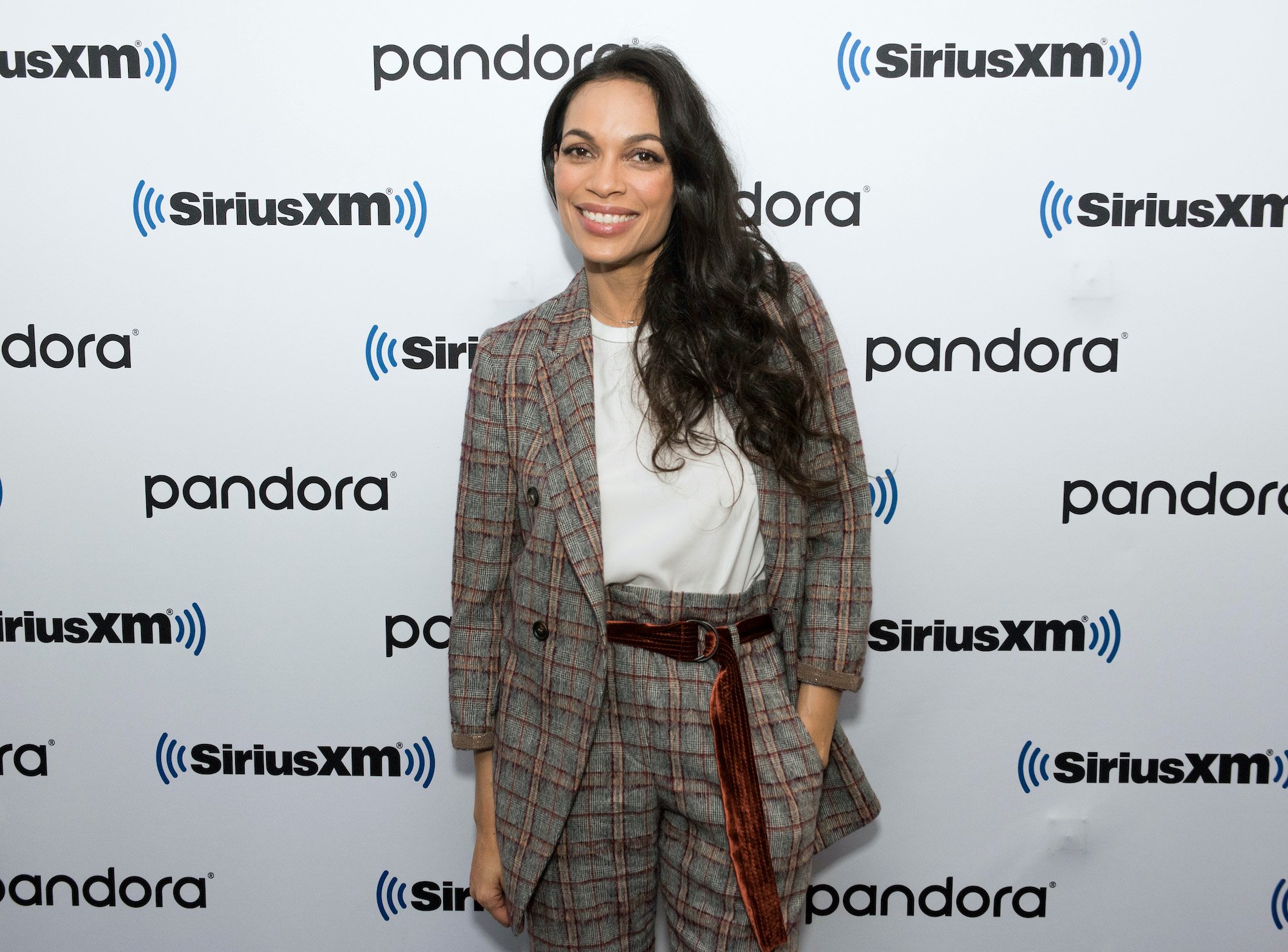 Rosario Dawson smiling in front of a white background