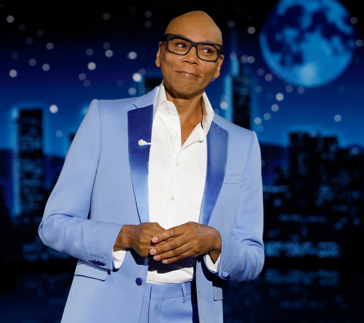 RuPaul smiling on stage wearing a blue suit at "Jimmy Kimmel Live!"