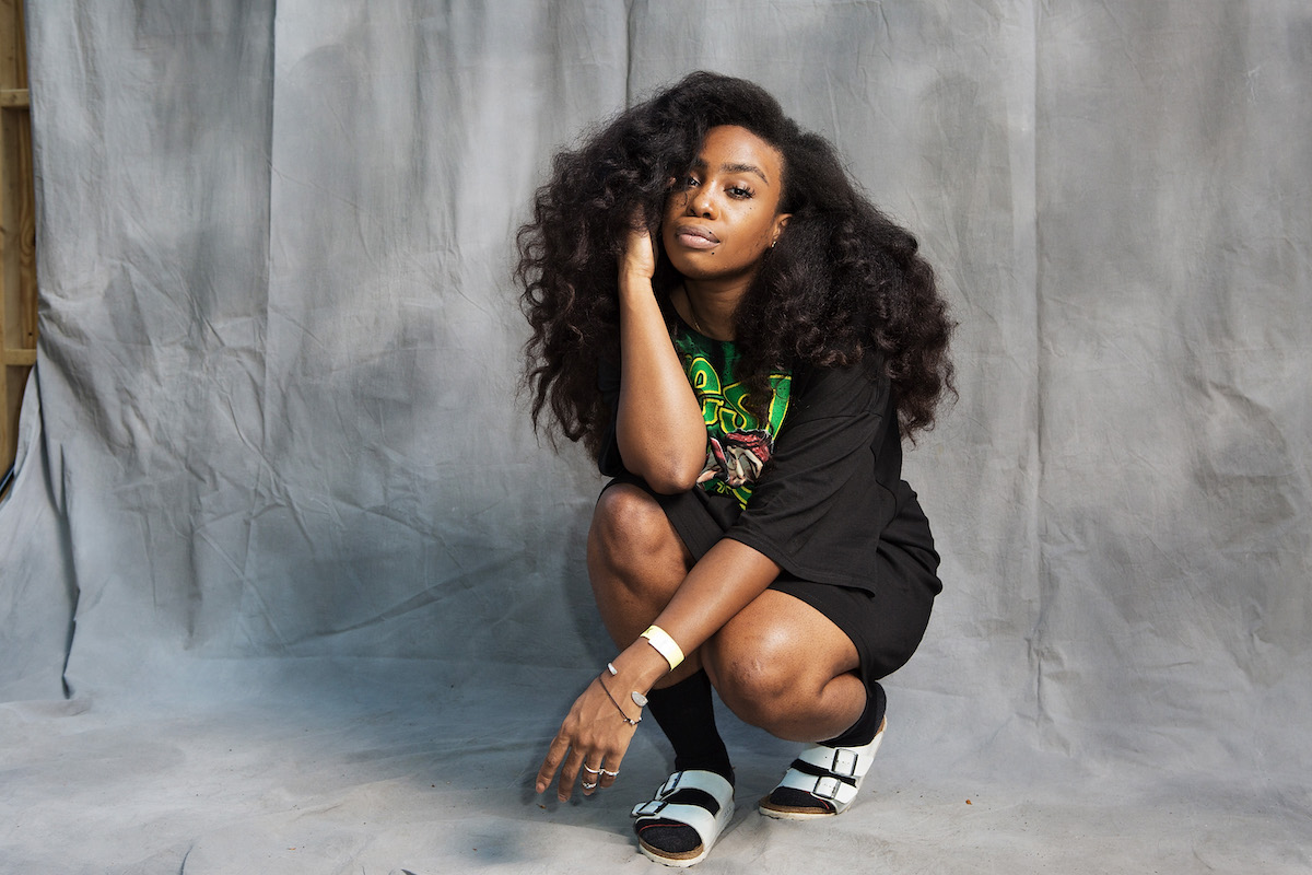 SZA in an all black shirt and biker shorts kneeling at Commodore Barry Park on August 24, 2014 in Brooklyn, New York.