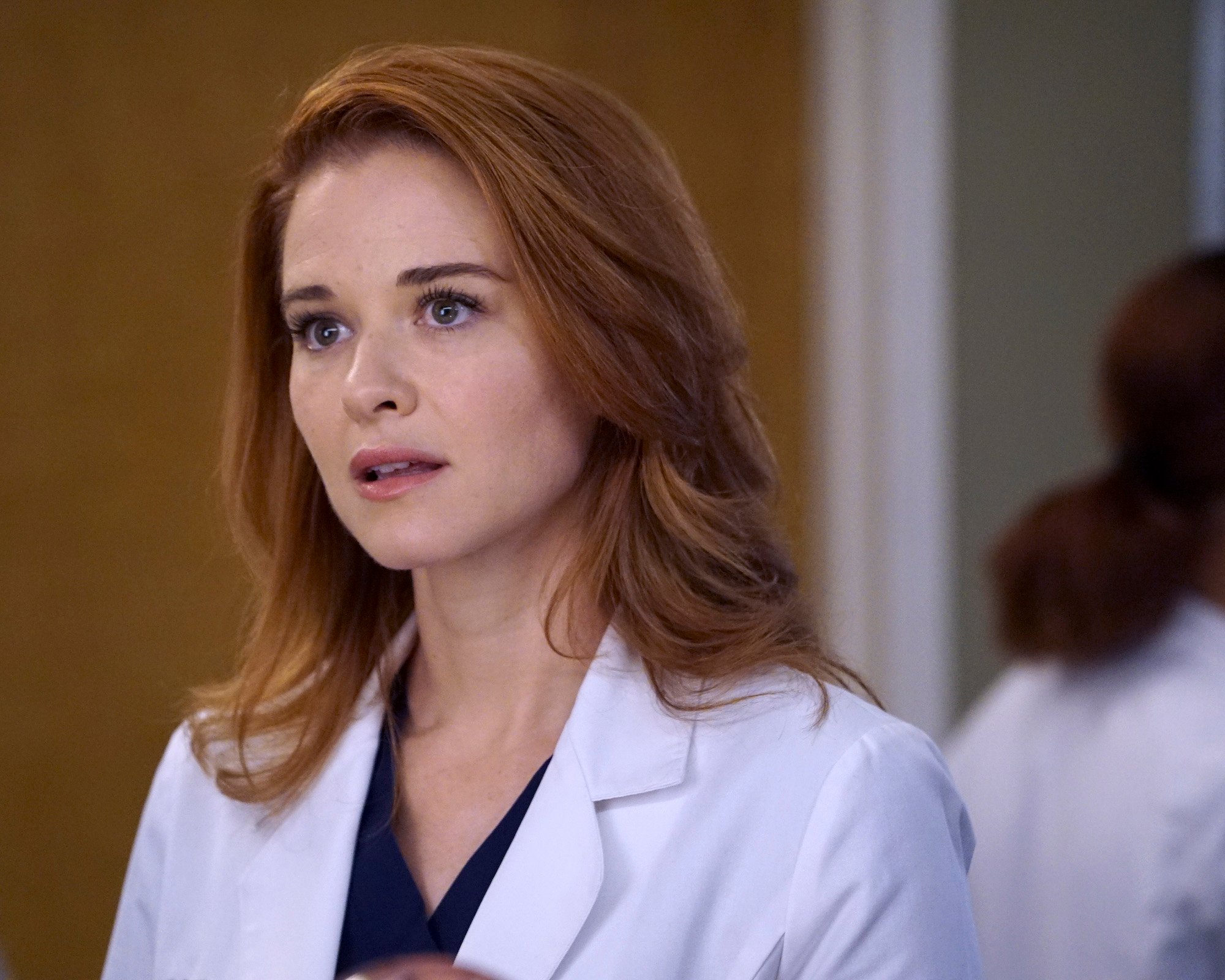 Sarah Drew wearing white scrubs in 'Grey's Anatomy' Season 13.