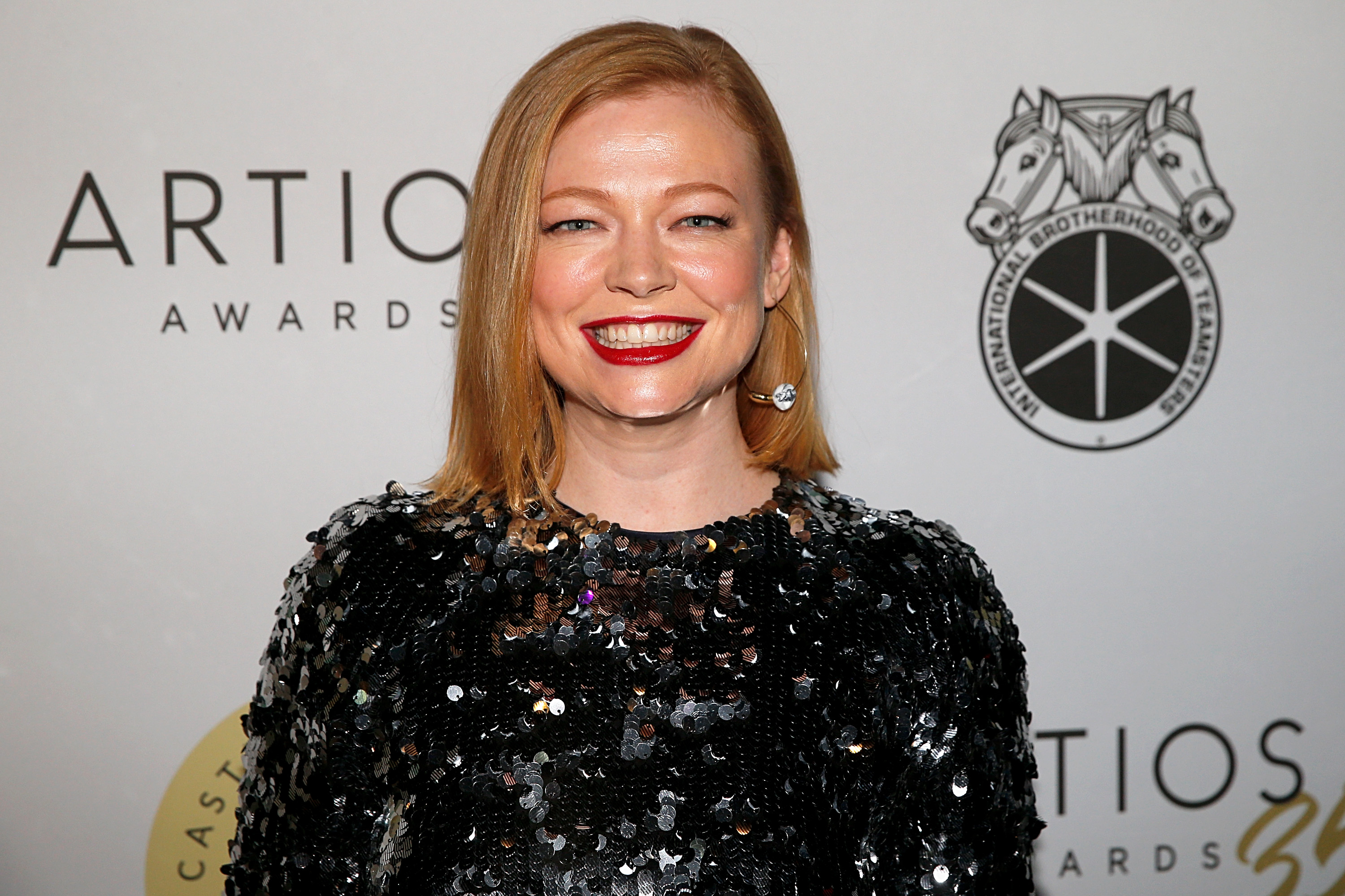 Sarah Snook smiling in a black shimmery dress from chest up.