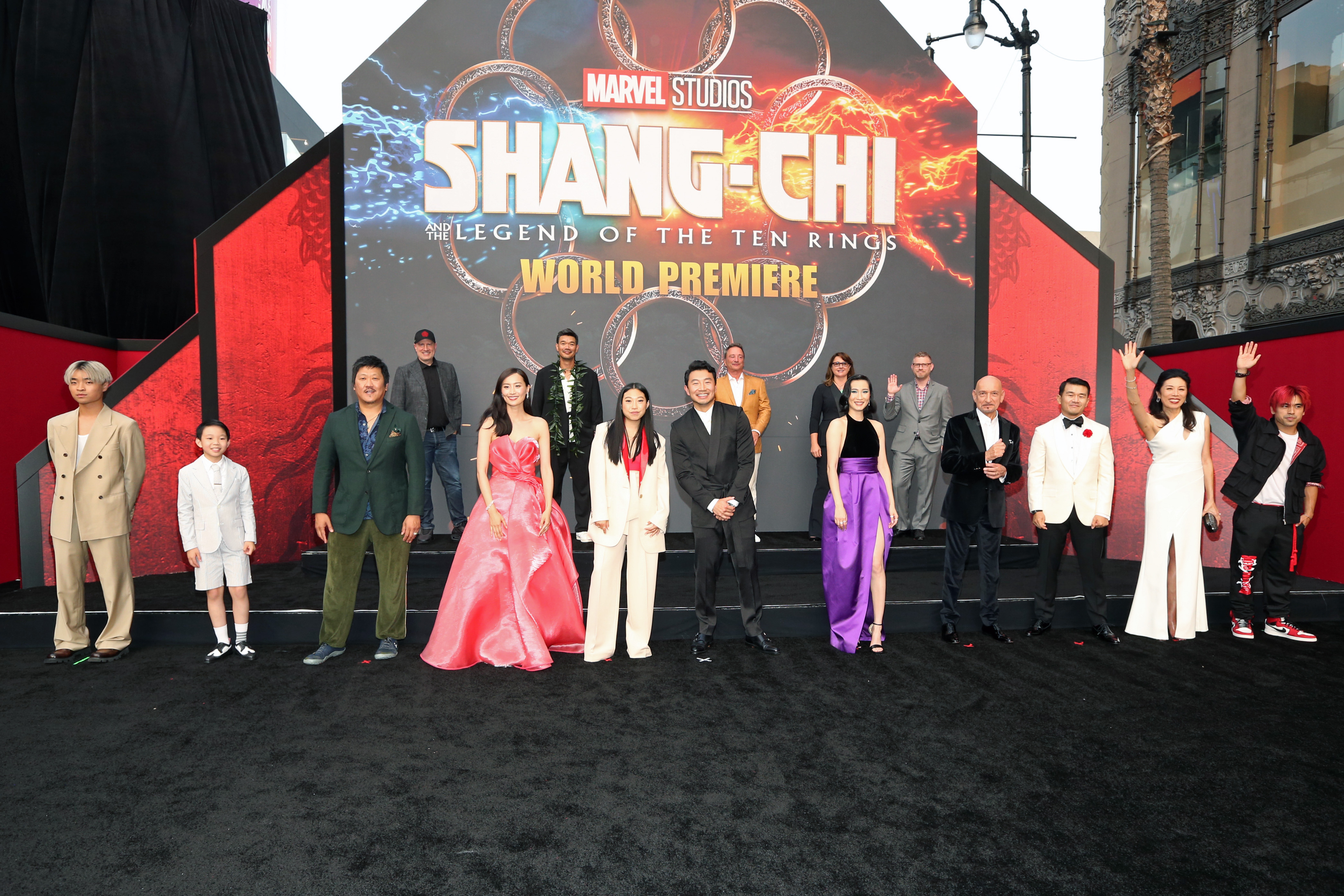 The cast and crew of 'Shang-Chi and the Legend of the Ten Rings' dressed formally and posed in front of a sign for the film at the world premiere.