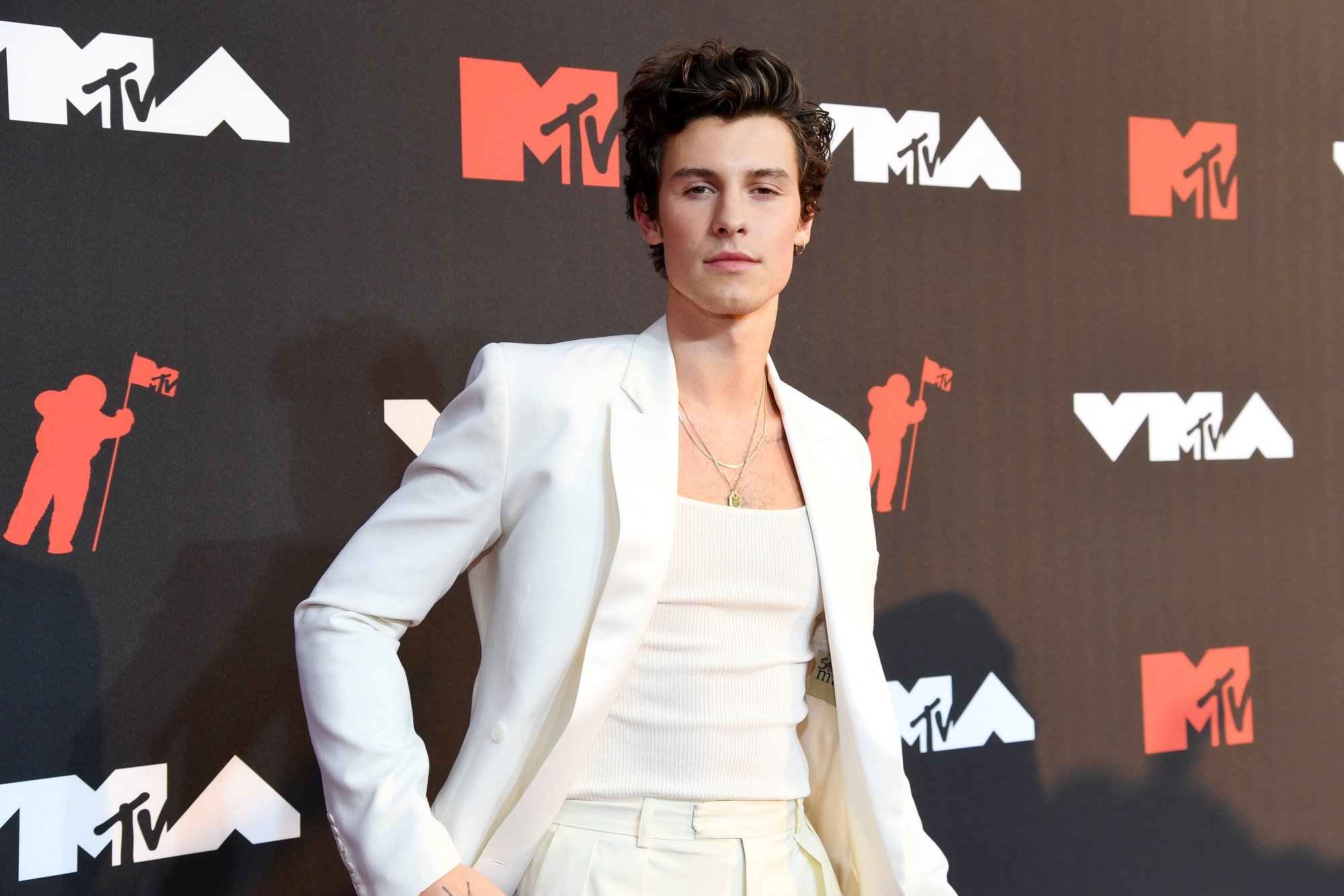 Shawn Mendes wears a white outfit in front of a backdrop at the 2021 MTV Video Music Awards