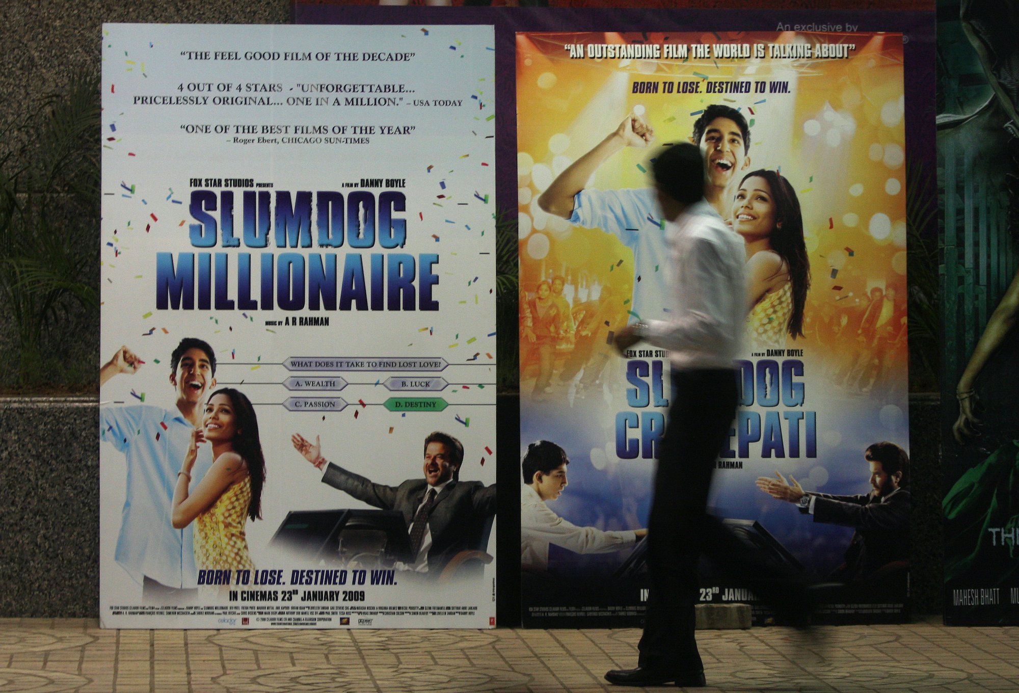 A person in front of a large banner of the movie Slumdog Millionaire
