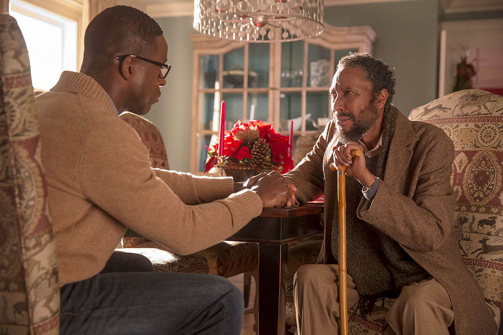 Sterling K. Brown as Randall Pearson and Ron Cephas Jones as William Hill sit at a table across from each other as they hold hands. There are red flowers between the. Williams also has a cane while they remain locked in this embrace.