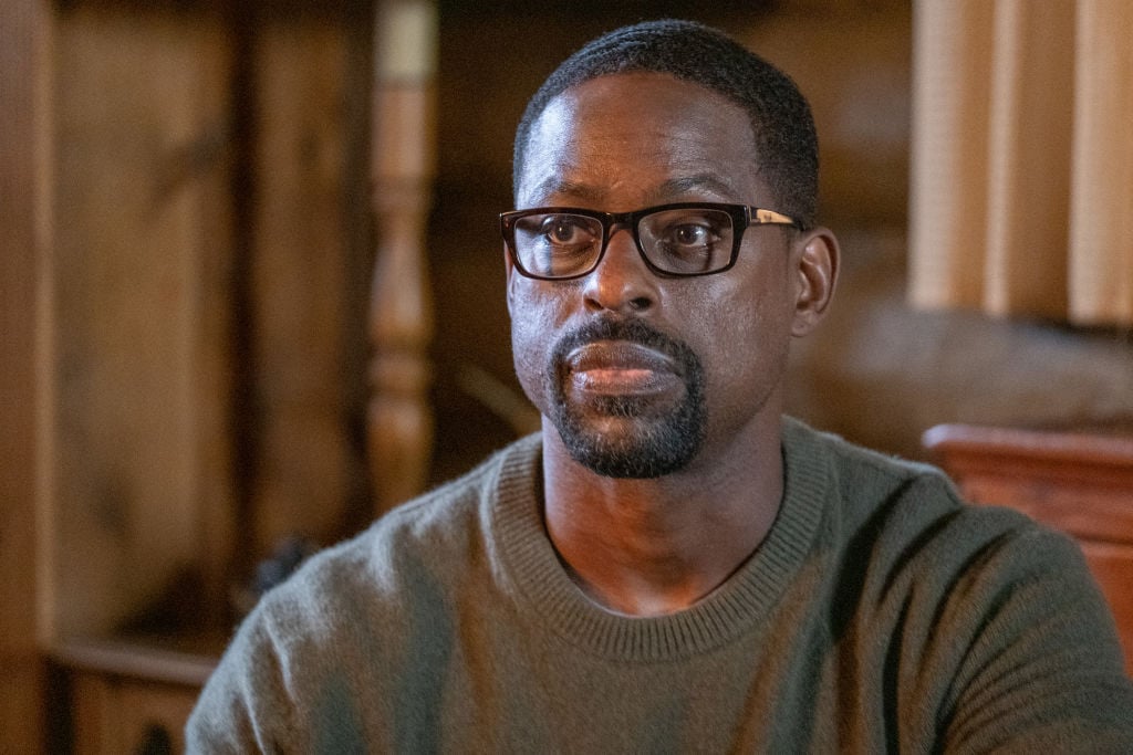 'This Is Us' star Sterling K. Brown as Randall Pearson sits looking out in a green sweater and glasses.