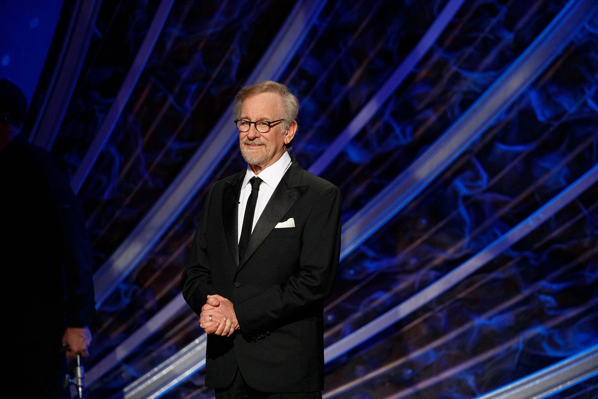 Steven Spielberg clasping his hands in front of him on stage.