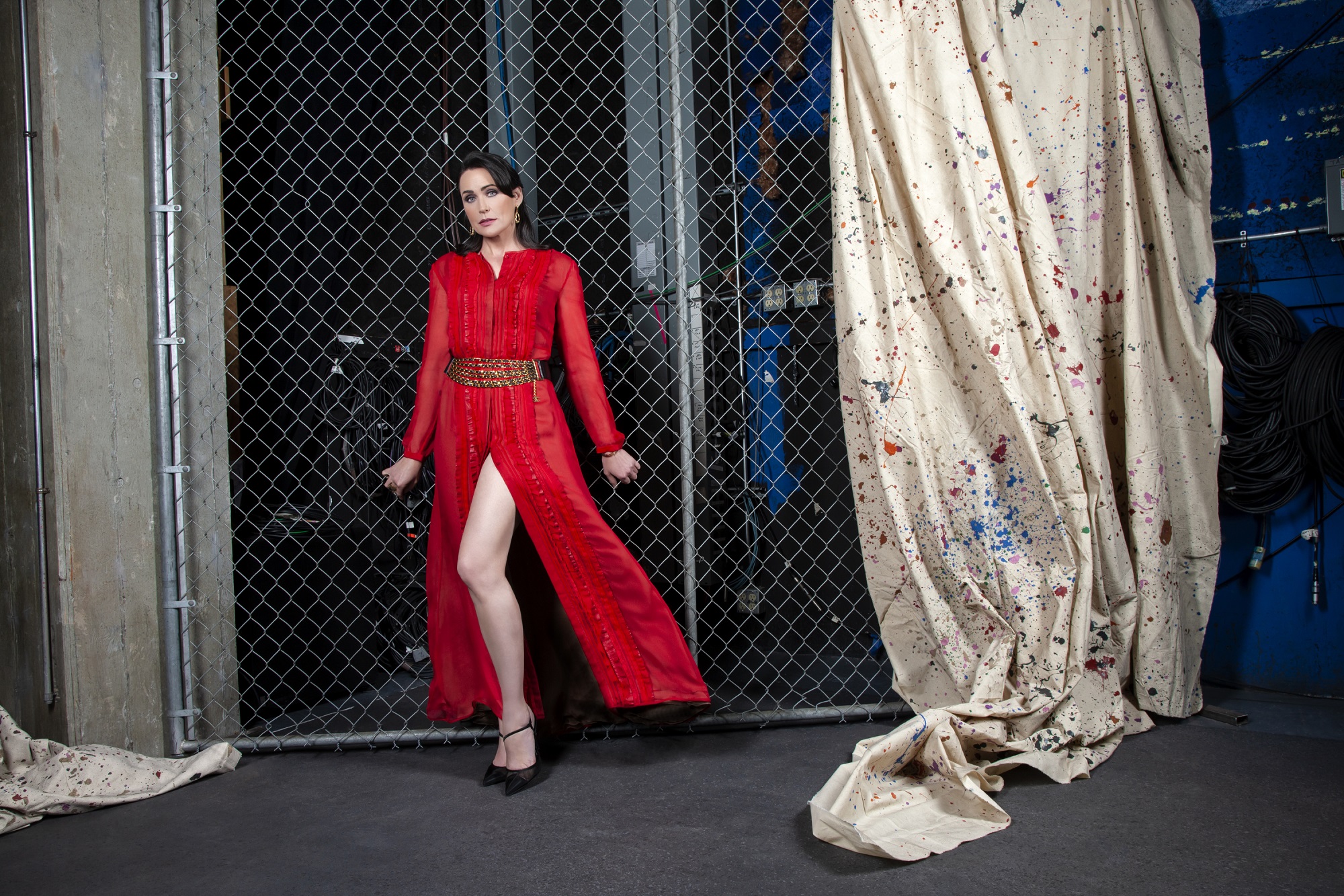 The Bold and the Beautiful spoilers focus on Rena Sofer's character of Quinn, pictured here in a red dress leaning up against a metal gate