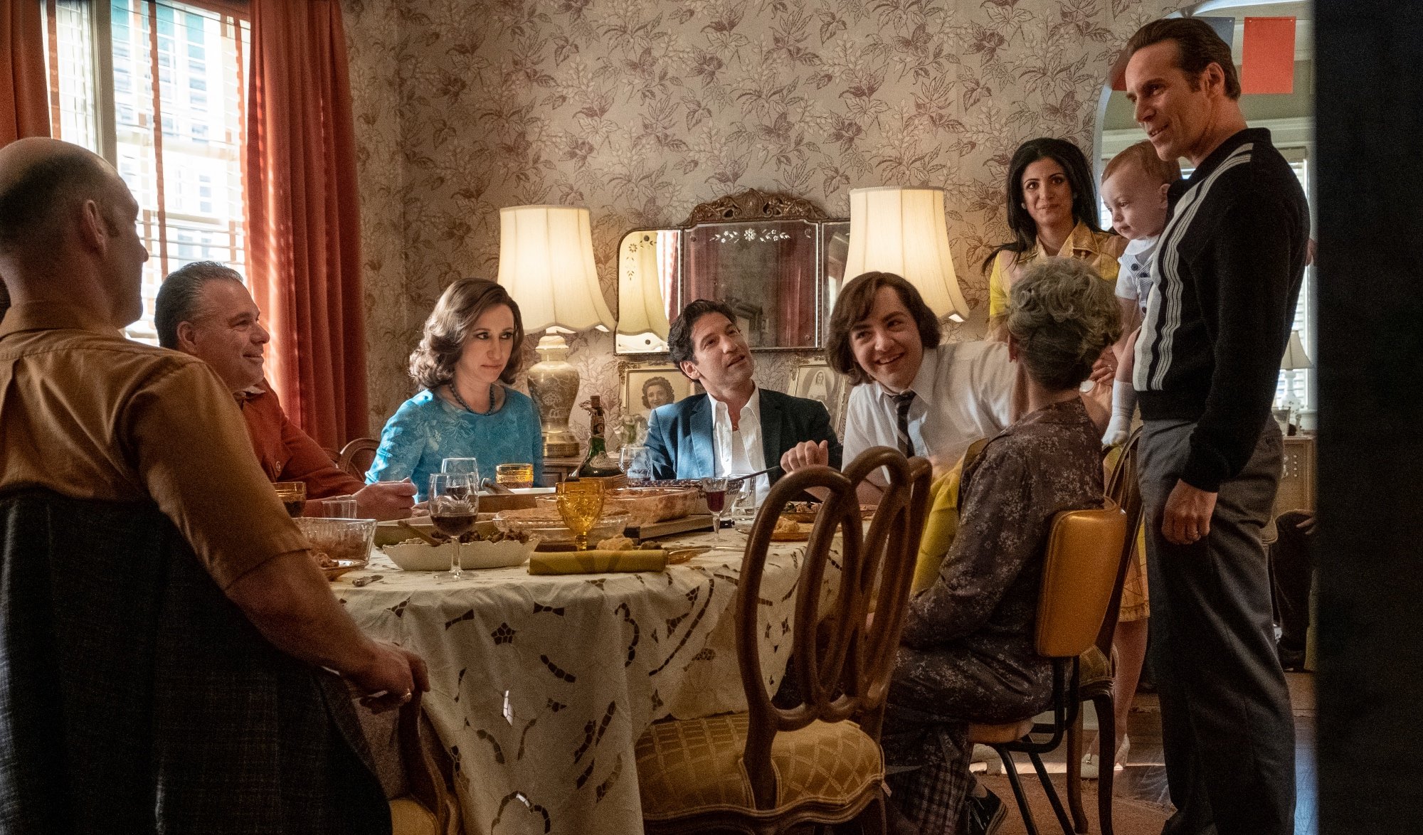 'The Many Saints of Newark' cast: Corey Stoll as Junior Soprano, Vera Farmia as Livia Soprano, Jon Bernthal as Johnny Soprano, Michael Gandolfini as Teenage Tony Soprano, Gabriella Piazza as Joanne Moltisanti, and Alessandro Nivola as Dickie Moltisanti all sitting around a table having a conversation in 'The Sopranos' prequel movie