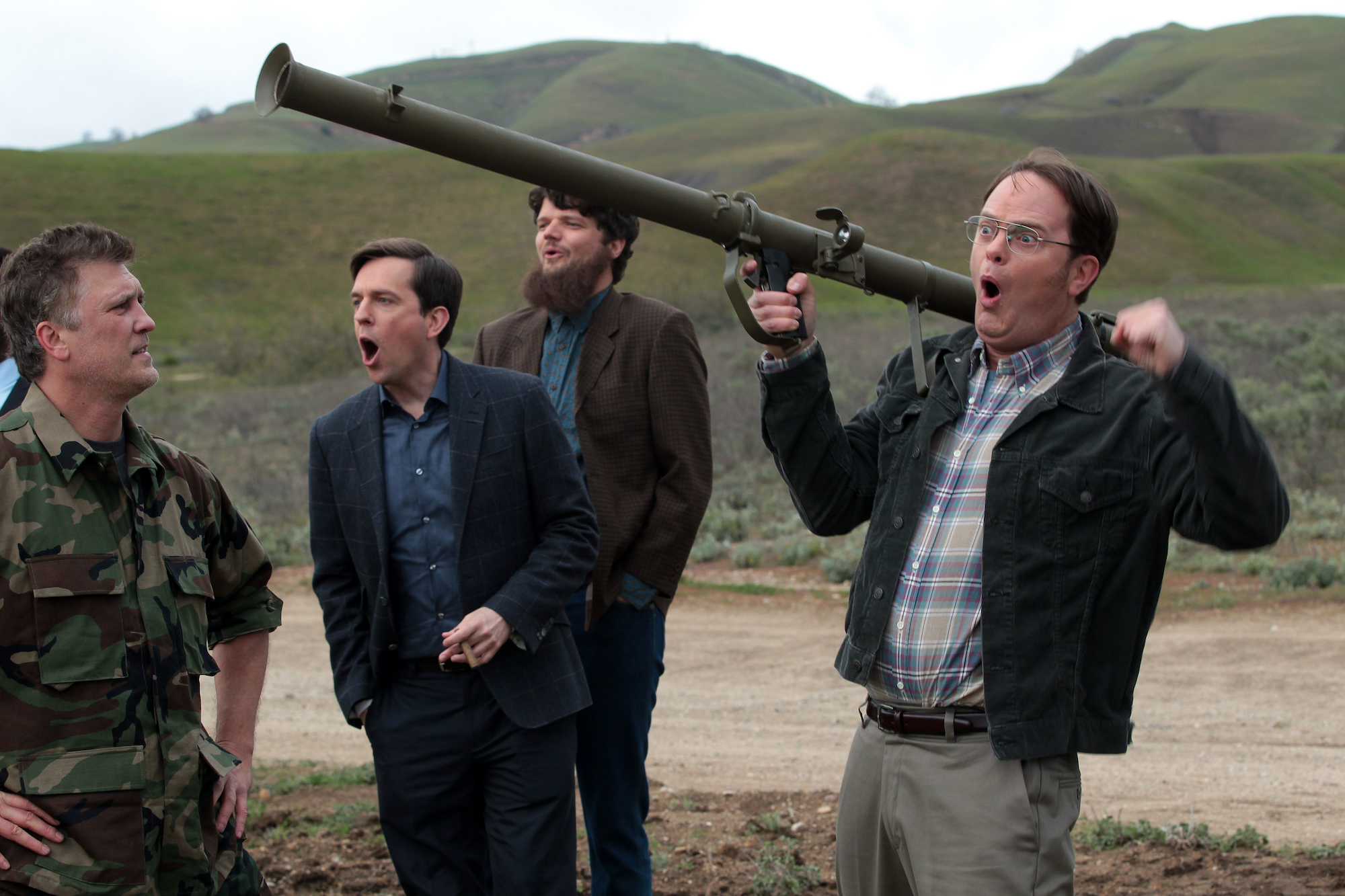 A still from season 9 of 'The Office' featuring a military man looking disapprovingly at Andy Bernard, played by Ed Helms, and Dwight Schrute, played by Rainn Wilson, who is holding a large gun