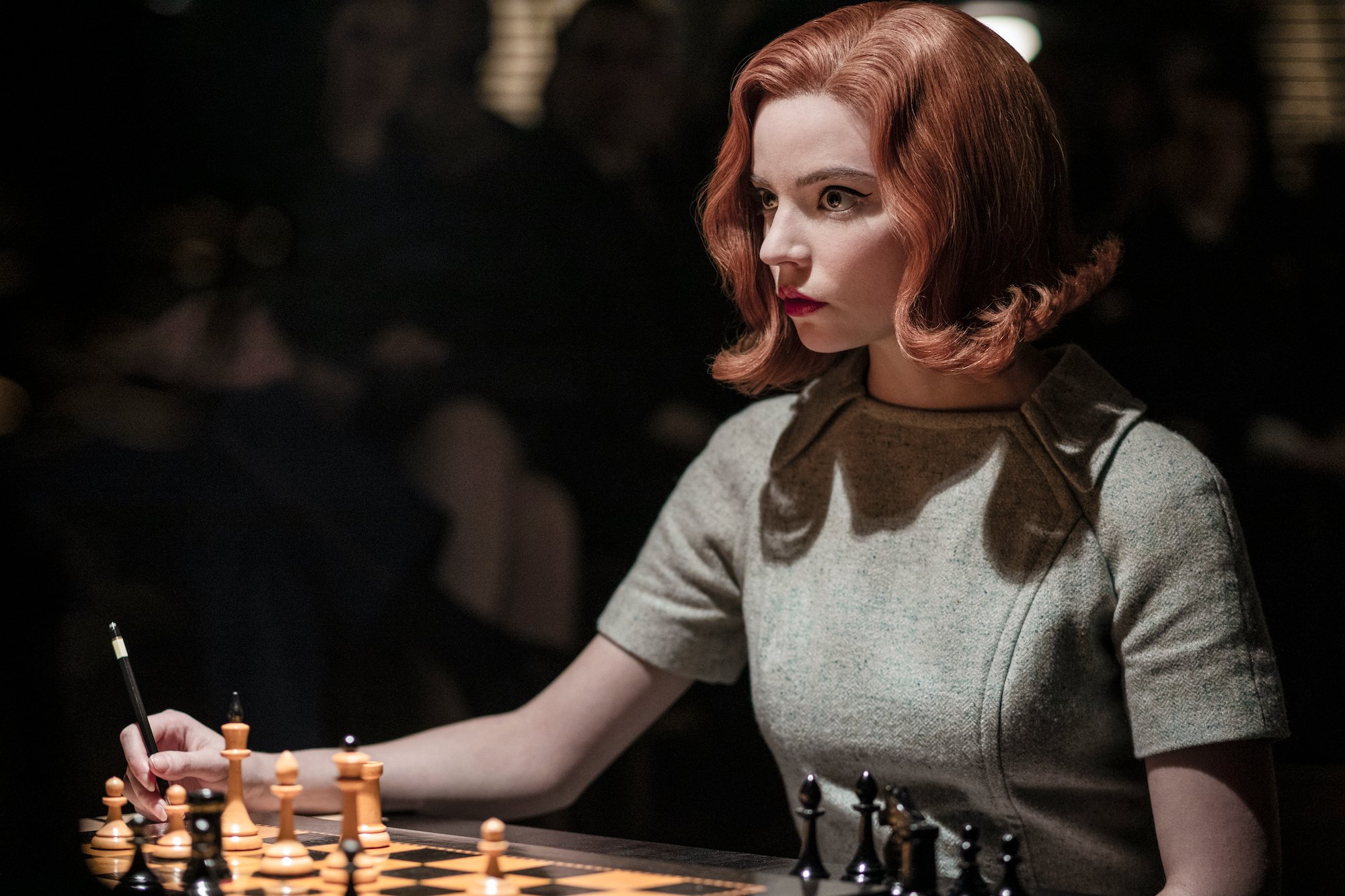 Anya Taylor-Joy as Beth Harmon sitting next to a chess board