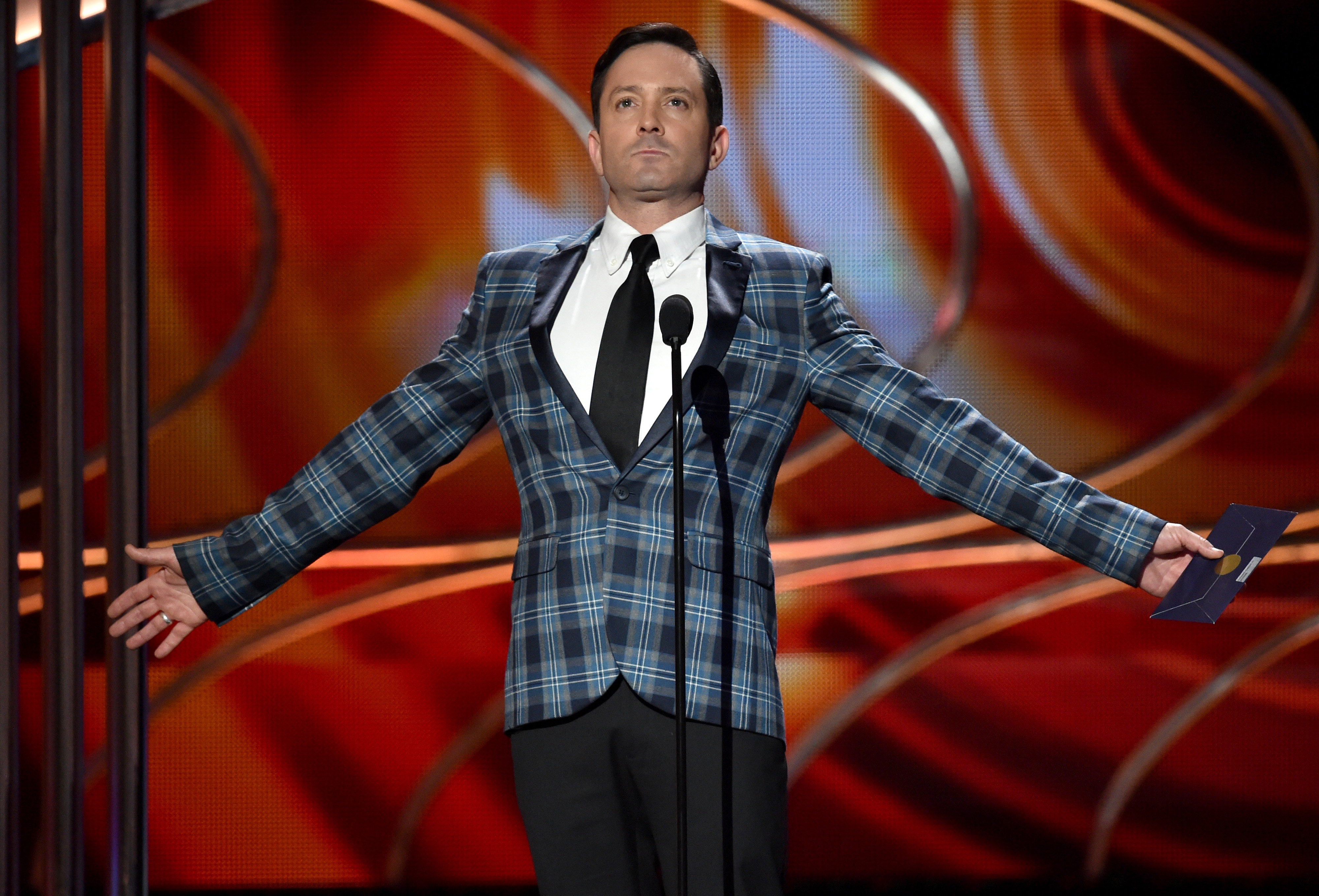 'Supergirl' actor Thomas Lennon wears a blue plaid suit onstage of an awards show.