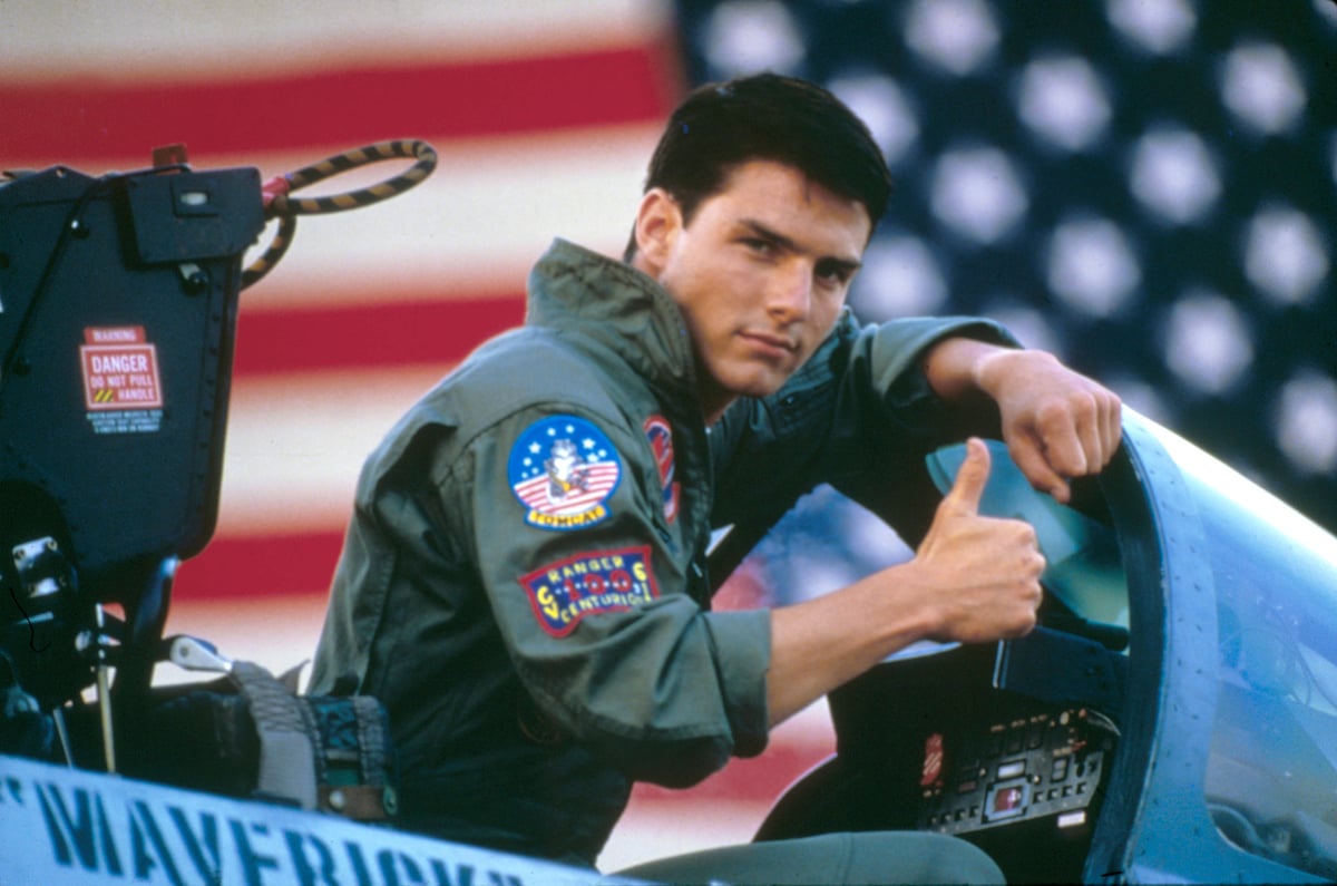 Tom Cruise giving a thumbs up, sitting in a plane on set of 'Top Gun'