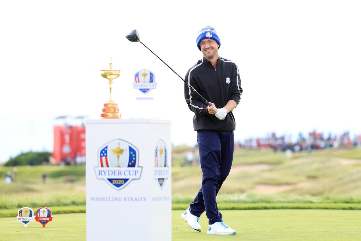 Tom Felton holds a golf club nest to a trophy at the Ryder Cup.