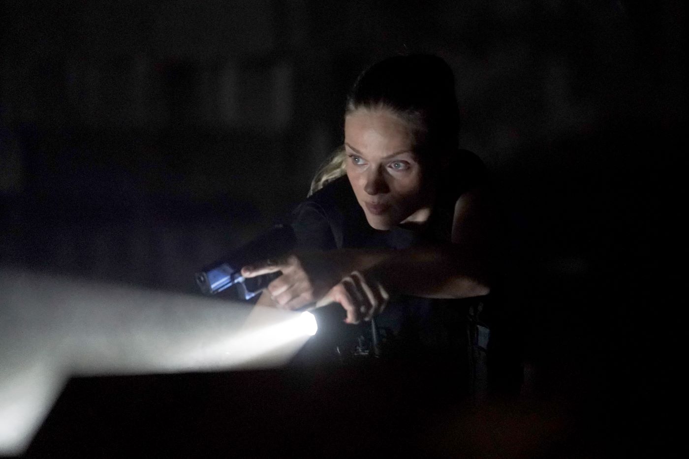 Tracy Spiridakos as Hailey from 'Chicago P.D.' in a dark room with a flashlight dressed as her character