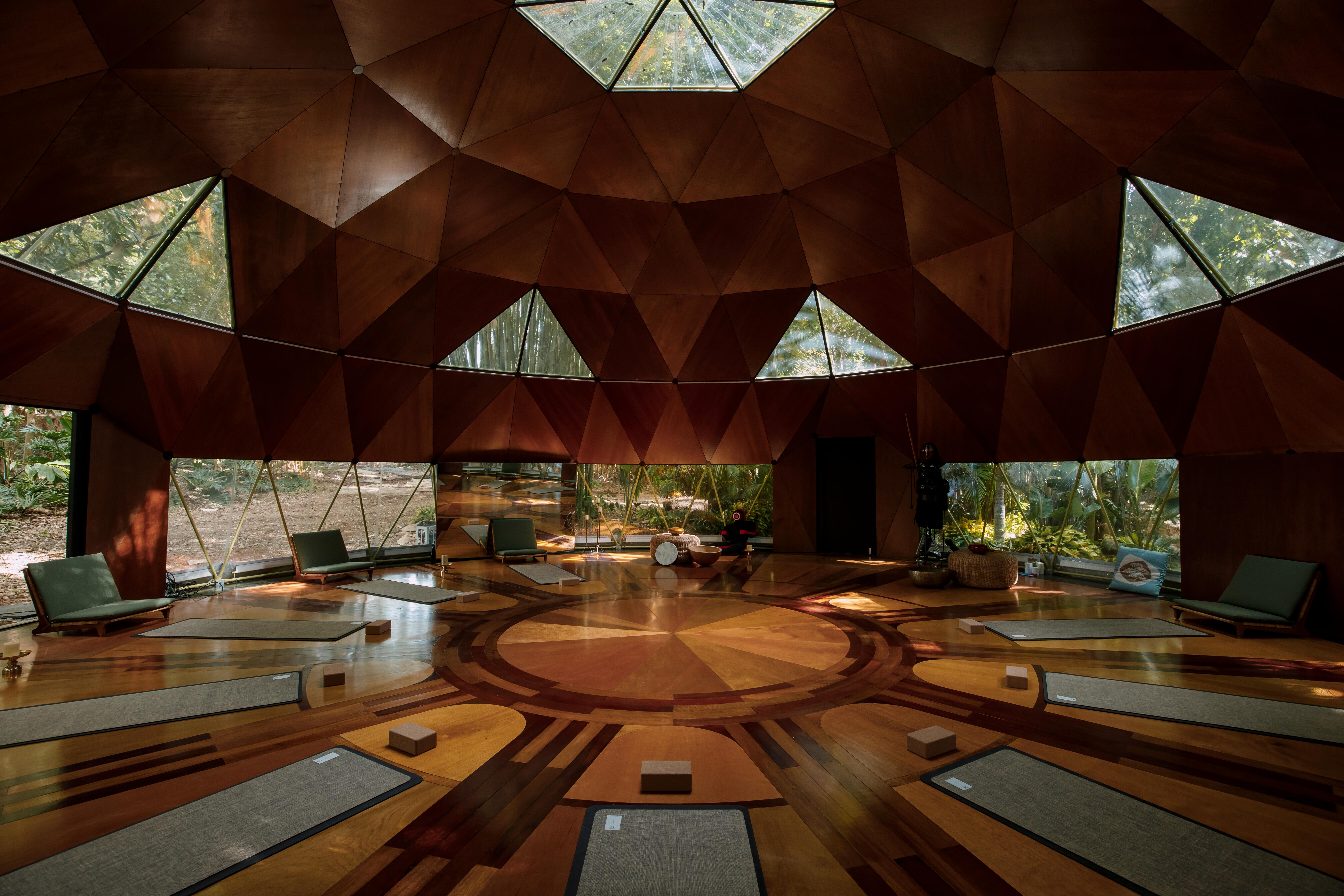 A large yoga/meditation room with big glass windows at Tranquillum House. Nine mats are placed on the floor awaiting guests.