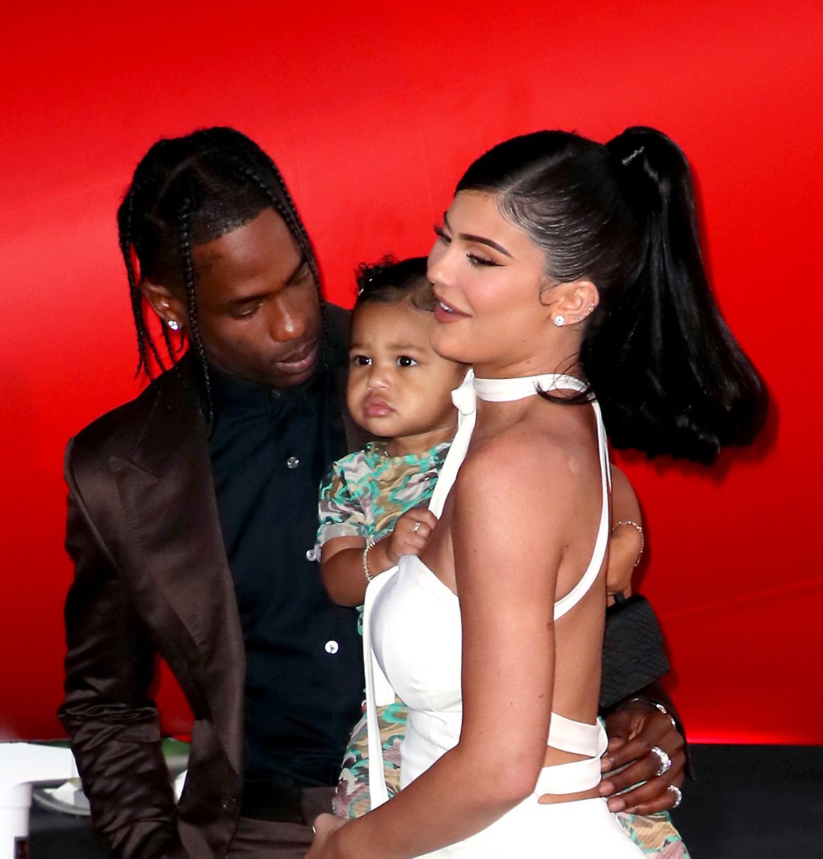 Travis Scott, Stormi Webster, and Kylie Jenner posing on the red carpet at his movie's premiere.