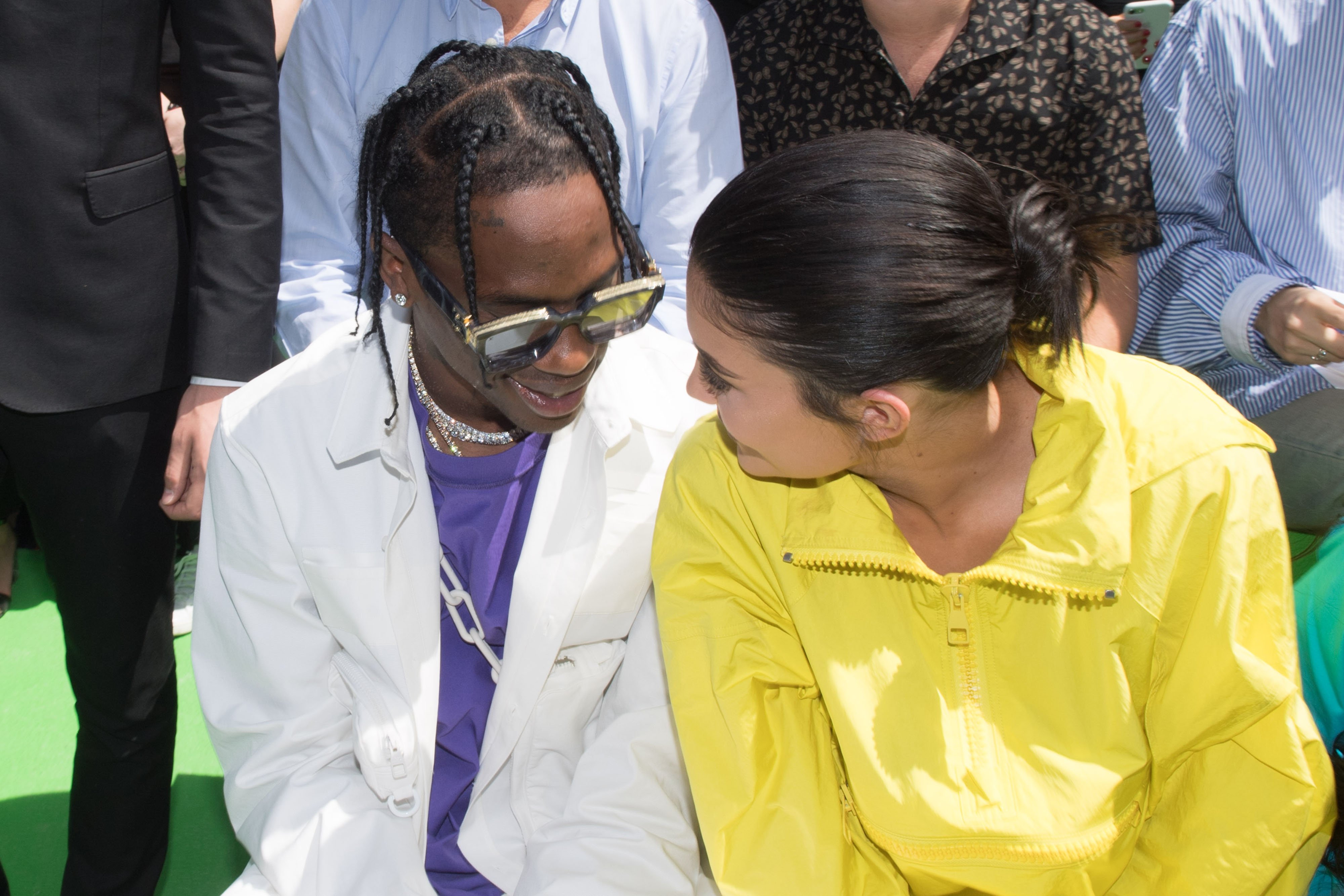 Travis Scott and Kylie Jenner looking at each other and smiling while attending a fashion show.