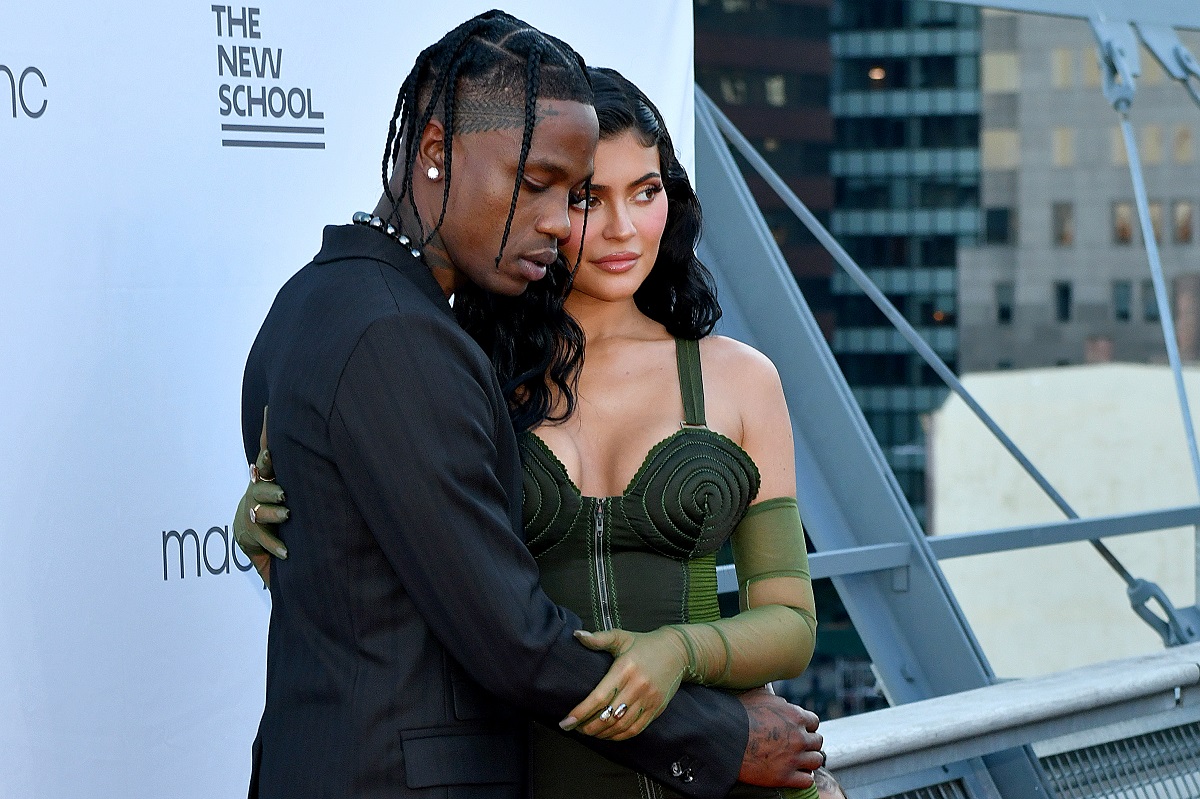 Travis Scott in a black suit and Kylie Jenner in a green dress.