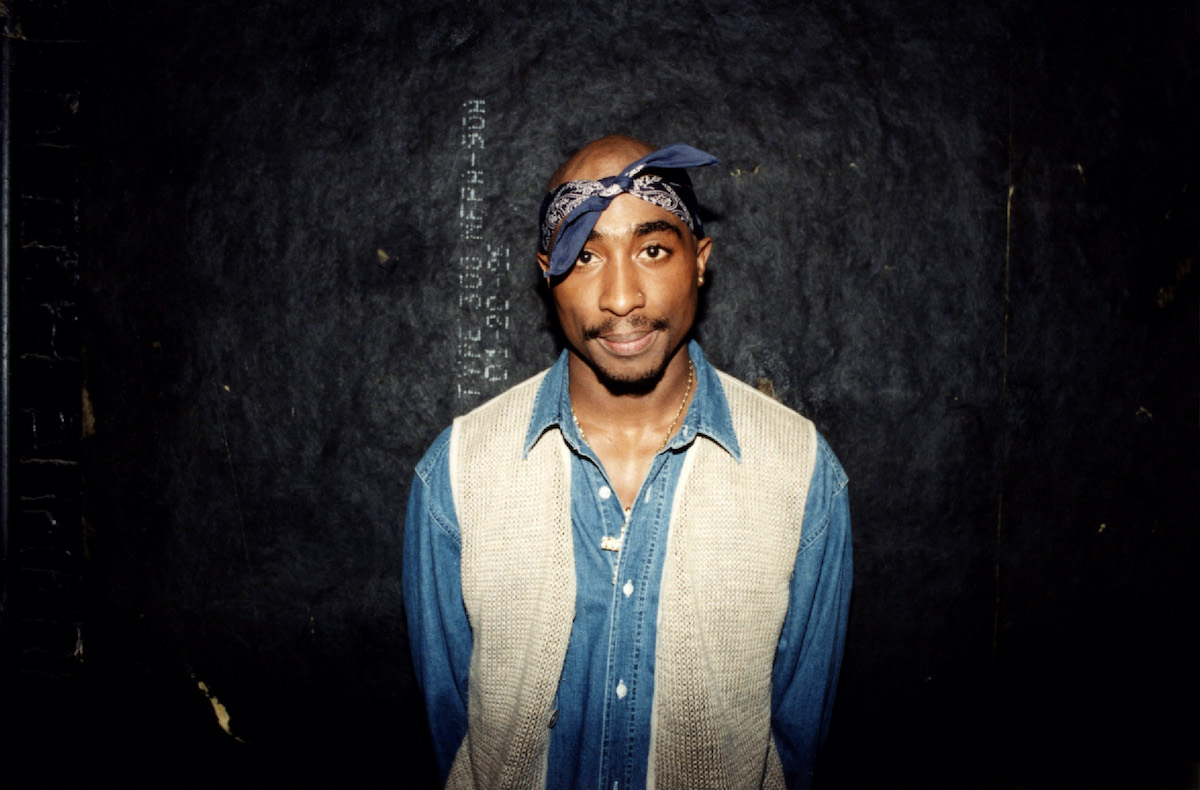 Tupac Shakur smiling in front of a black background