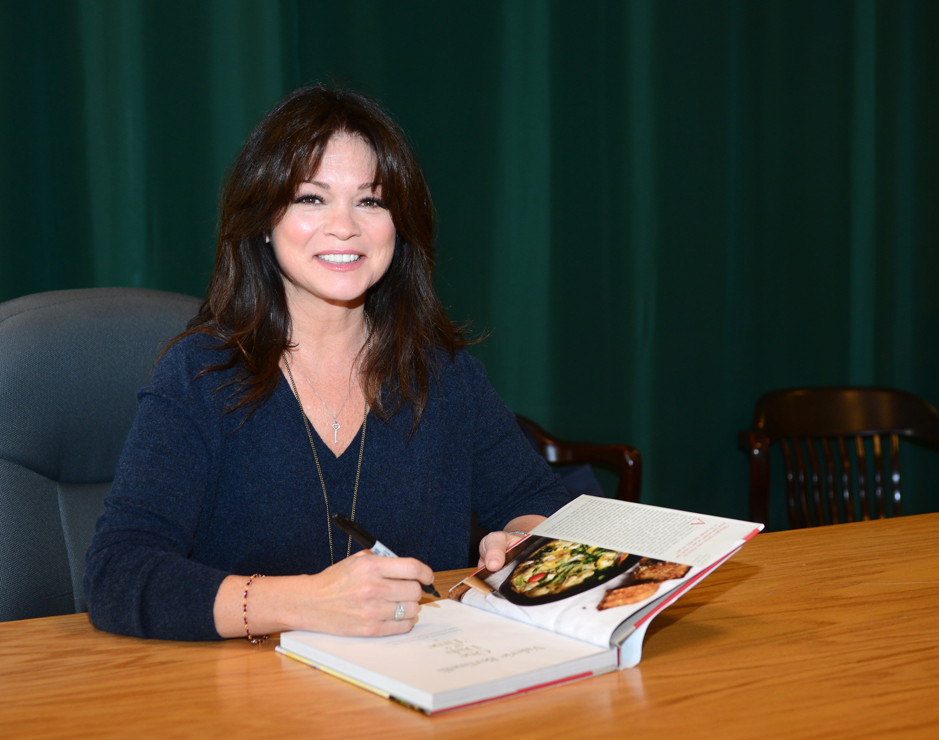 Food Network star Valerie Bertinelli smiles as she signs a copy of her cookbook