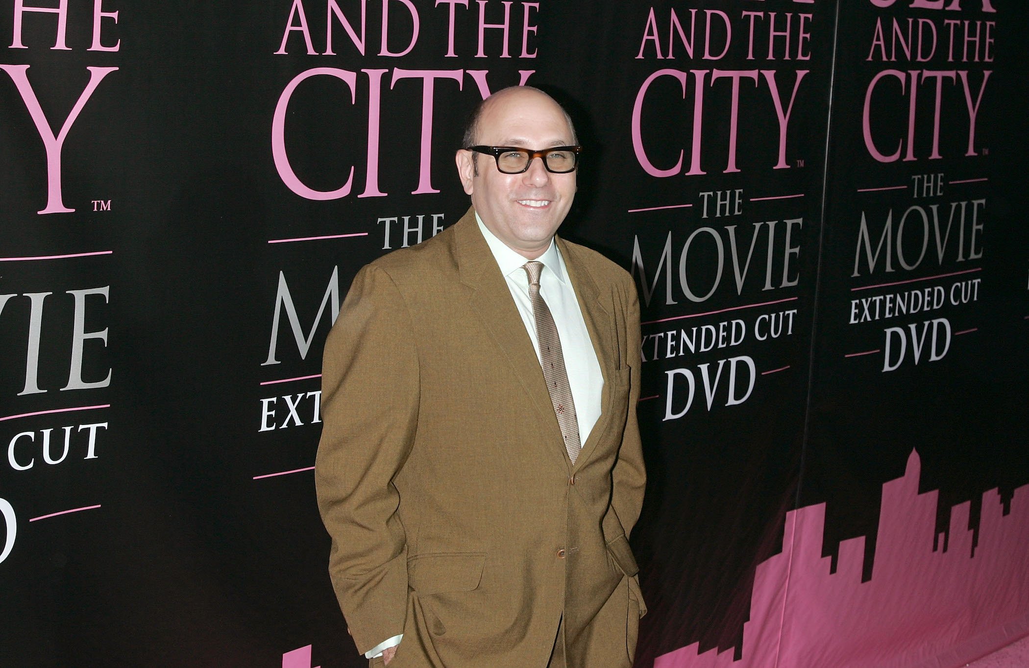 Willie Garson standing in front of a 'Sex and the City' sign. Willie Garson's net worth raised exponentially thanks to his role on the series.