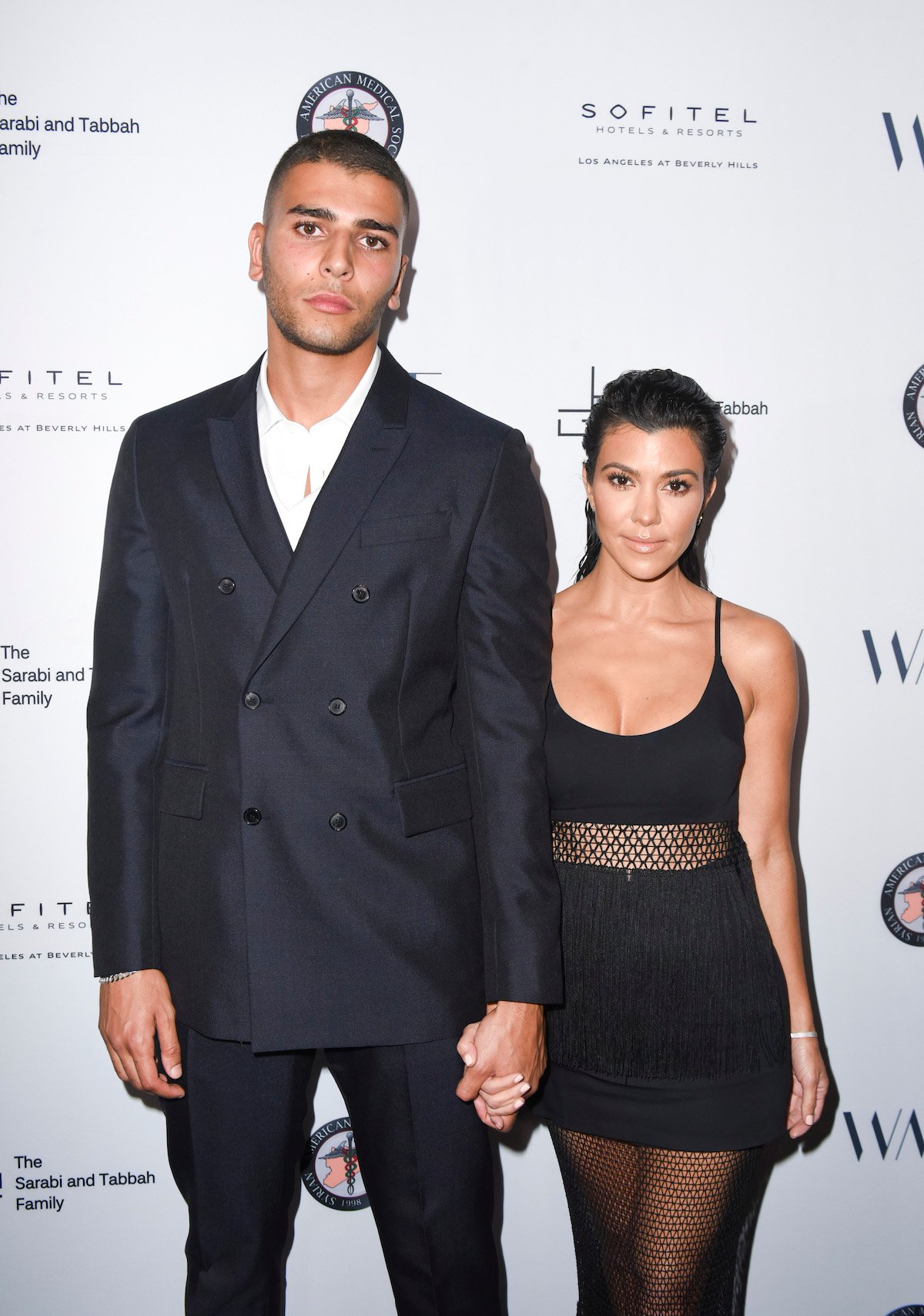 Younes Bendjima and Kourtney Kardashian pose for the camera together at an event.