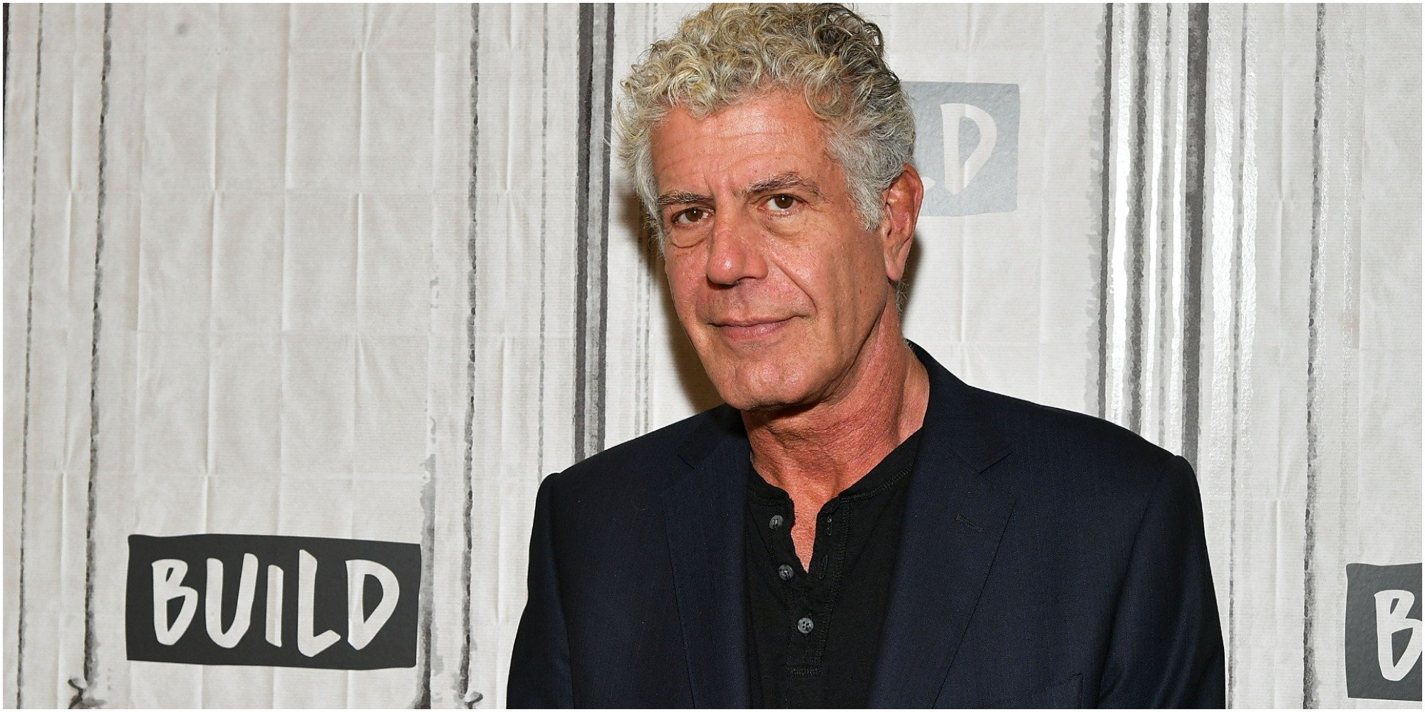 Anthony Bourdain smiles wearing a black outfit 