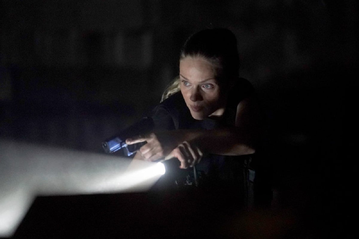Tracy Spiridakos as Hailey Upton on Chicago P.D. Season 9 -- Upton shines a flashlight while bracing her pistol over her wrist.