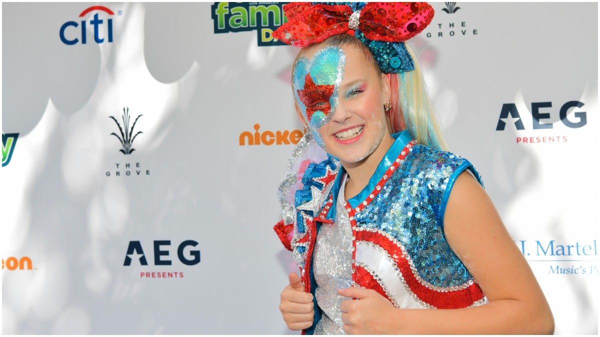 JoJo Siwa poses in a glittery outfit on the red carpet.