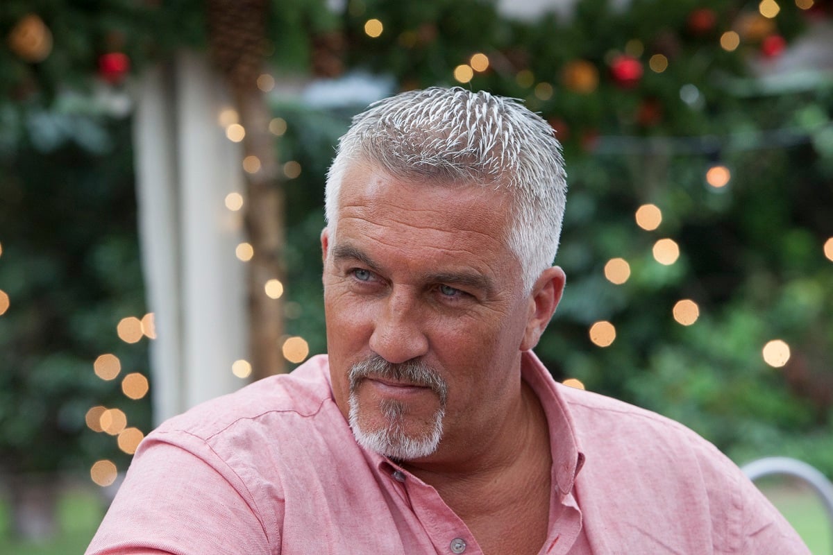 Paul Hollywood of The Great British Baking Show -- Paul wears a salmon button down and looks into the left middle distance.