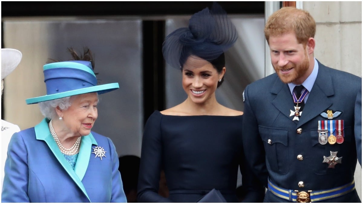 Queen Elizabeth, Meghan Markle, Prince Harry pose at a royal event.