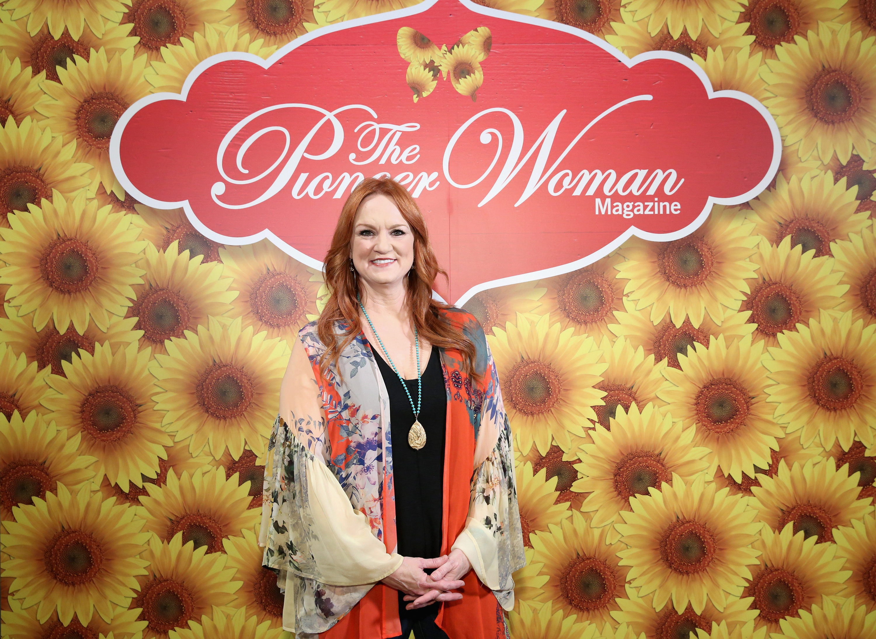 Ree Drummond poses in front of a backdrop with the 'Pioneer Woman' logo