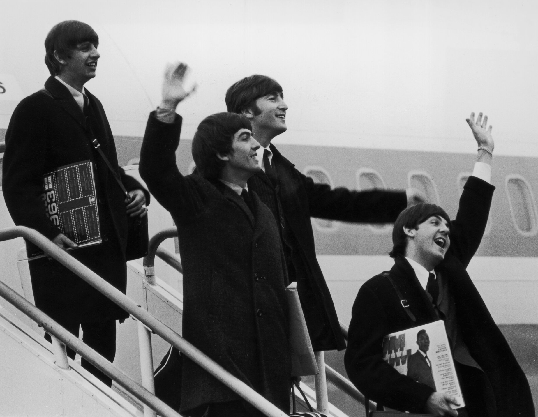 The Beatles (left to right: Ringo Starr, George Harrison, John Lennon, and Paul McCartney) step off the plane which brought them back from their tour of the United States.