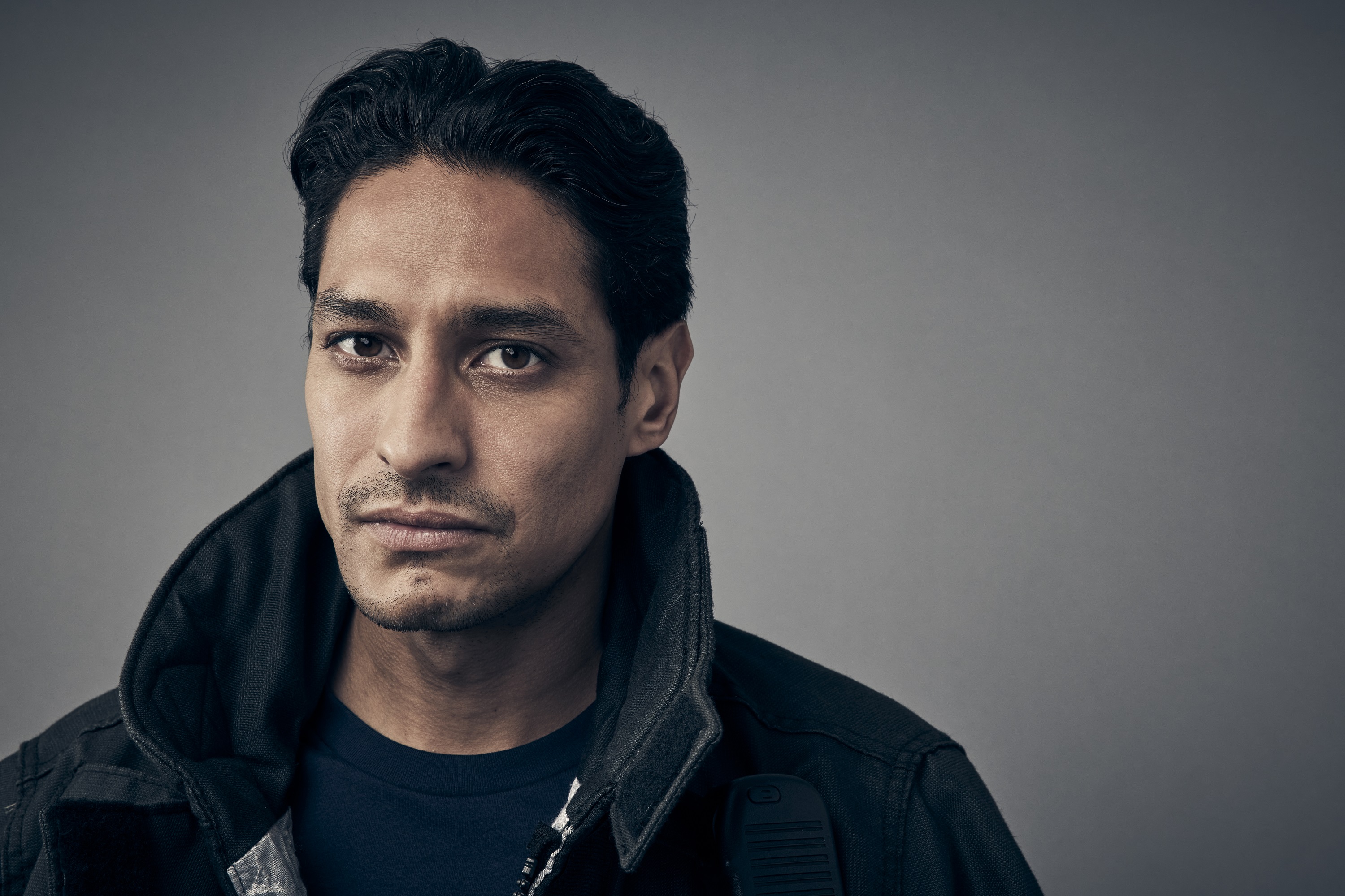 Station 19 Season 5 cast member Carlos Miranda posing for a photo as Theo Ruiz