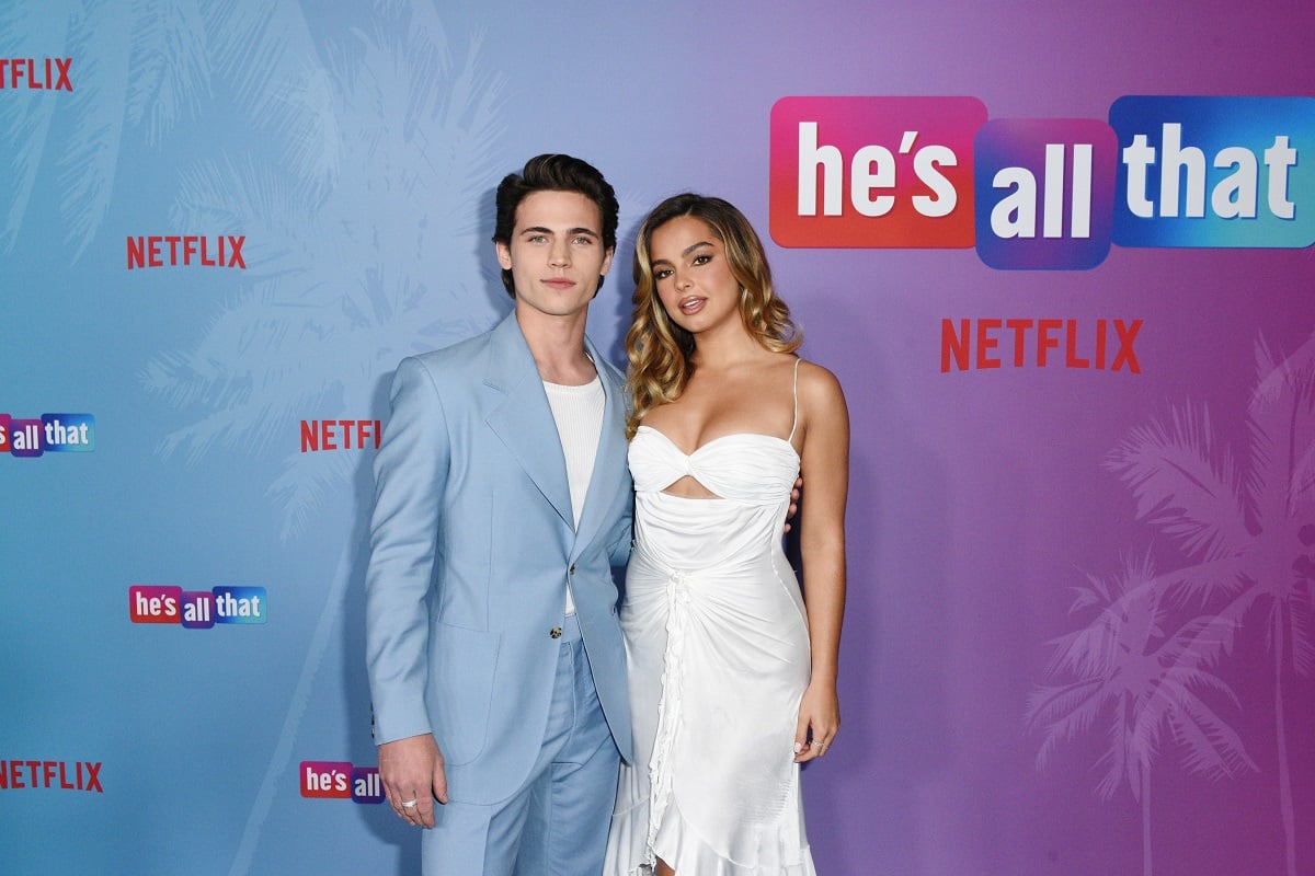 'He's All That' stars Tanner Buchanan, wearing a blue suit, and Addison Rae, wearing a white dress, stand side-by-side and pose for photographers.