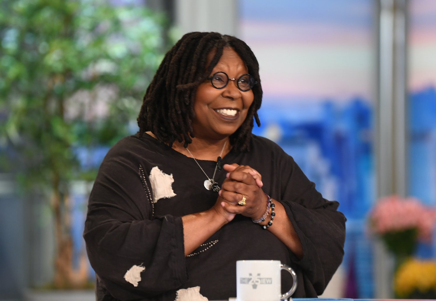 Whoopi Goldberg smiles as she holds her hands together