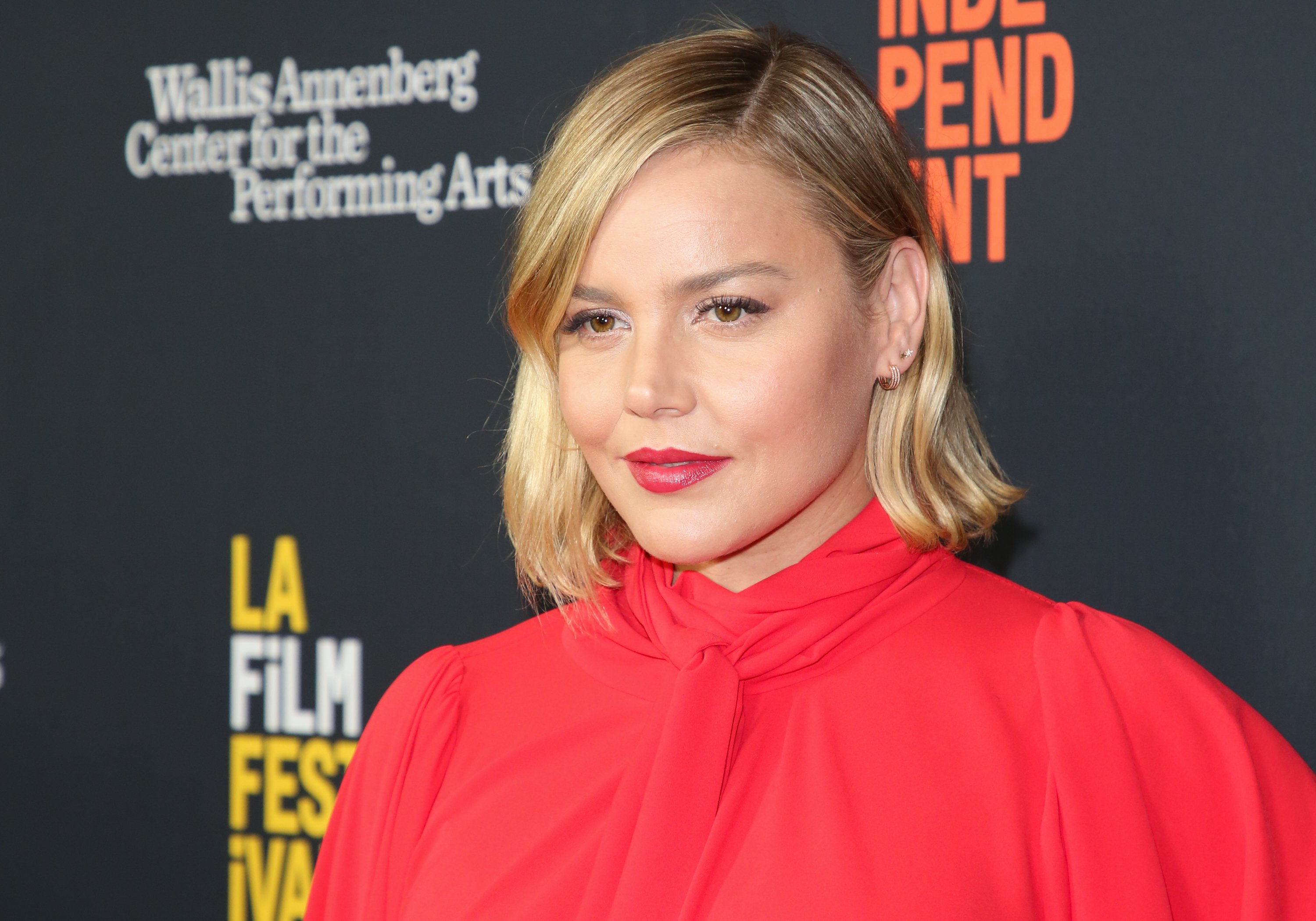 Abbie Cornish of 'Jack Ryan' wearing a red blouse on the red carpet of a 'Free Solo' screening