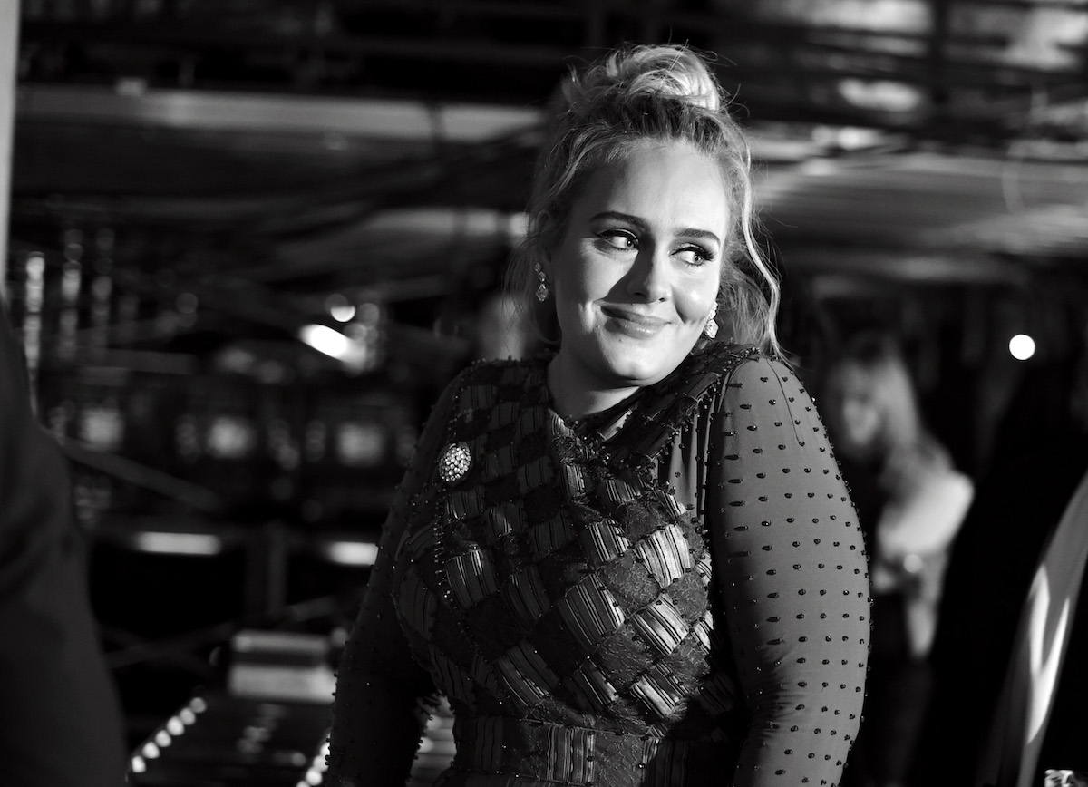 Black and white photo of Adele smiling and looking away from the camera.