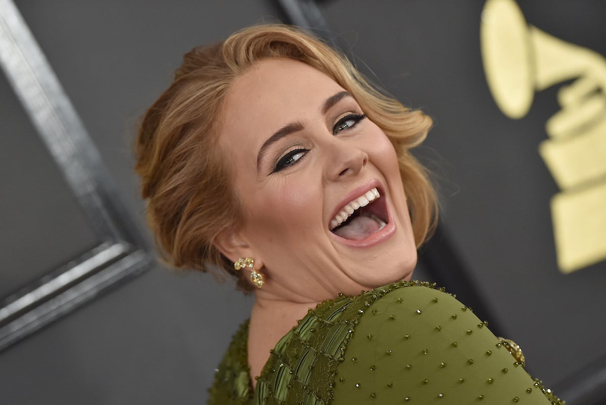 Adele wears a green dress and laughs at an event.