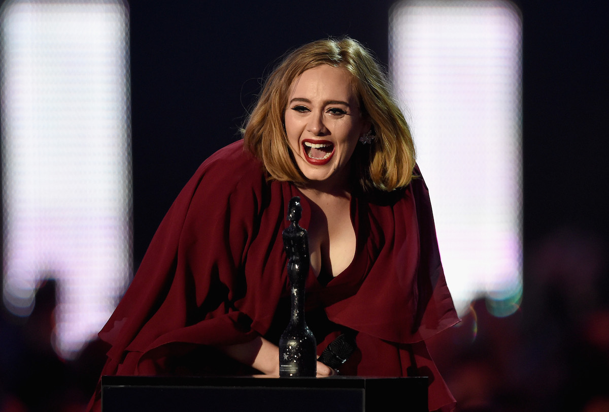Adele smiling on stage wearing a red dress.
