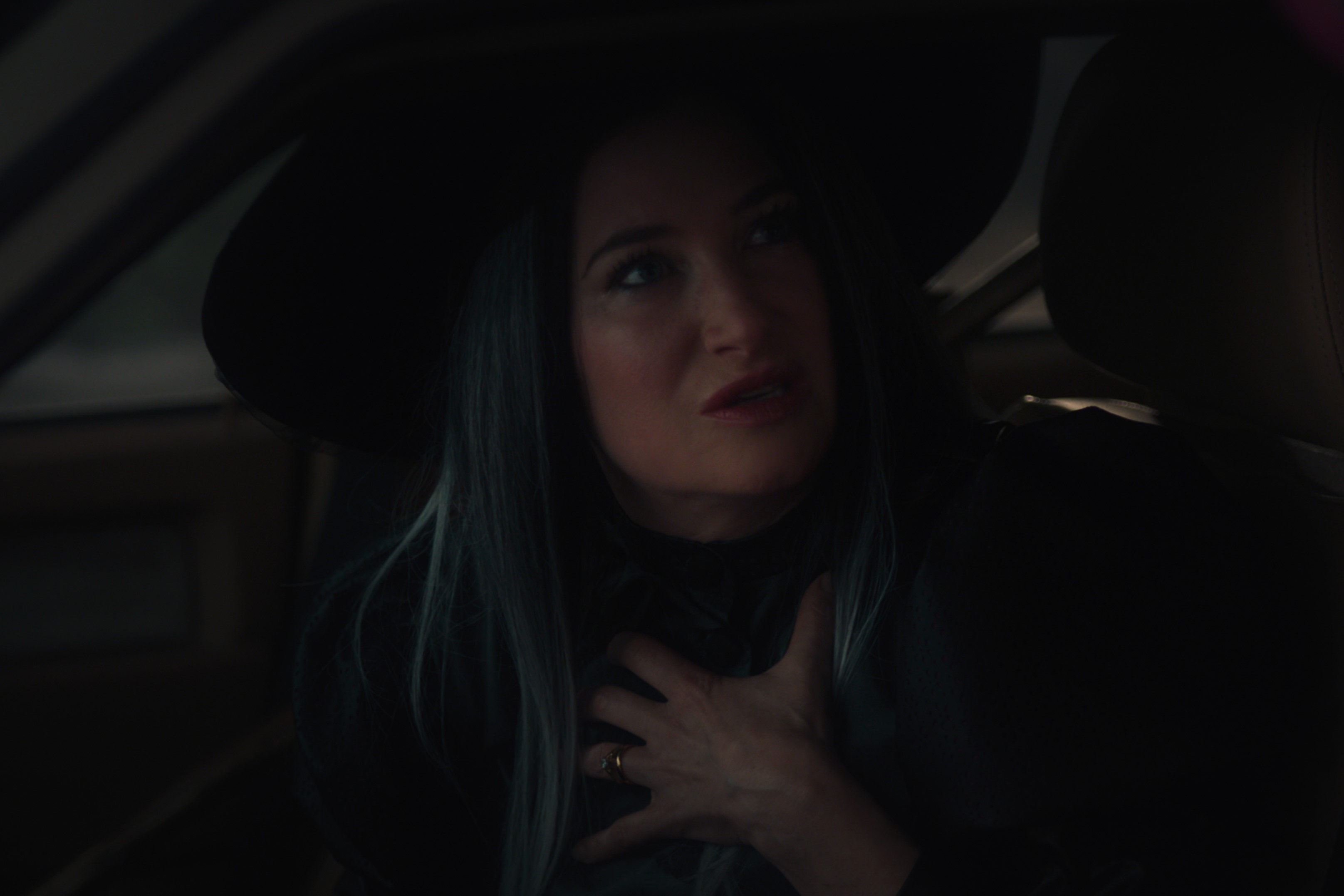 'WandaVision' actor Kathryn Hahn, as her character Agatha Harkness, wears a witch hat and puts her hand over her chest.