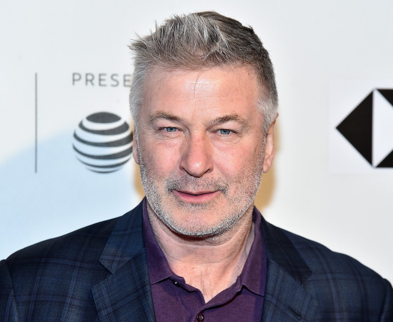 Alec Baldwin looking on in front of white background