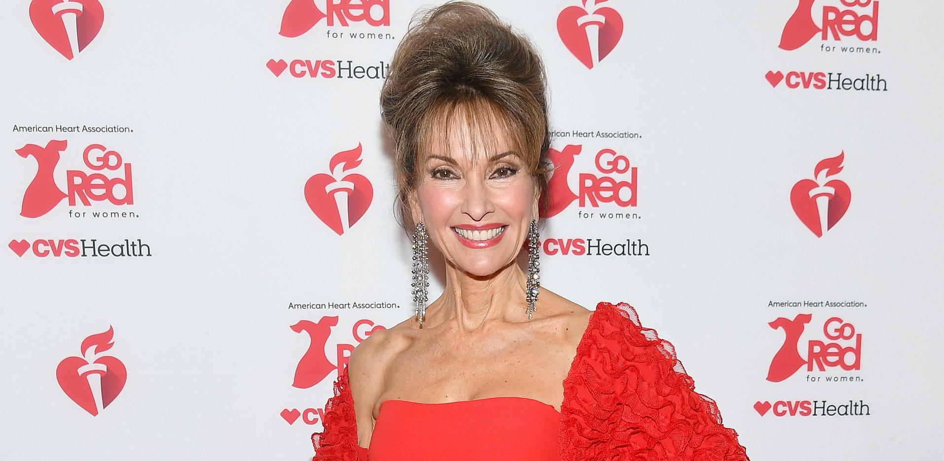 Susan Lucci of All My Children in a red dress on a red and white step and repeat