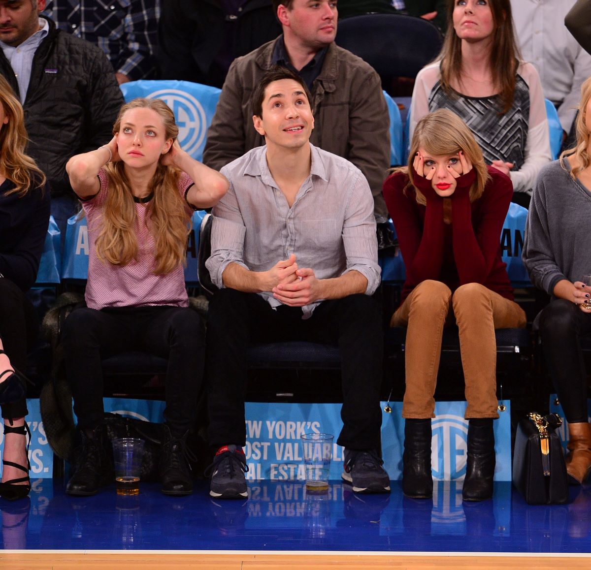 Amanda Seyfried, Justin Long and Taylor Swift seated at a basketball game