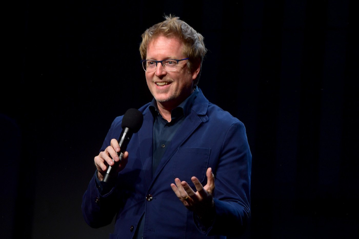 Andrew Stanton, Pixar director, holding a microphone at a conference.