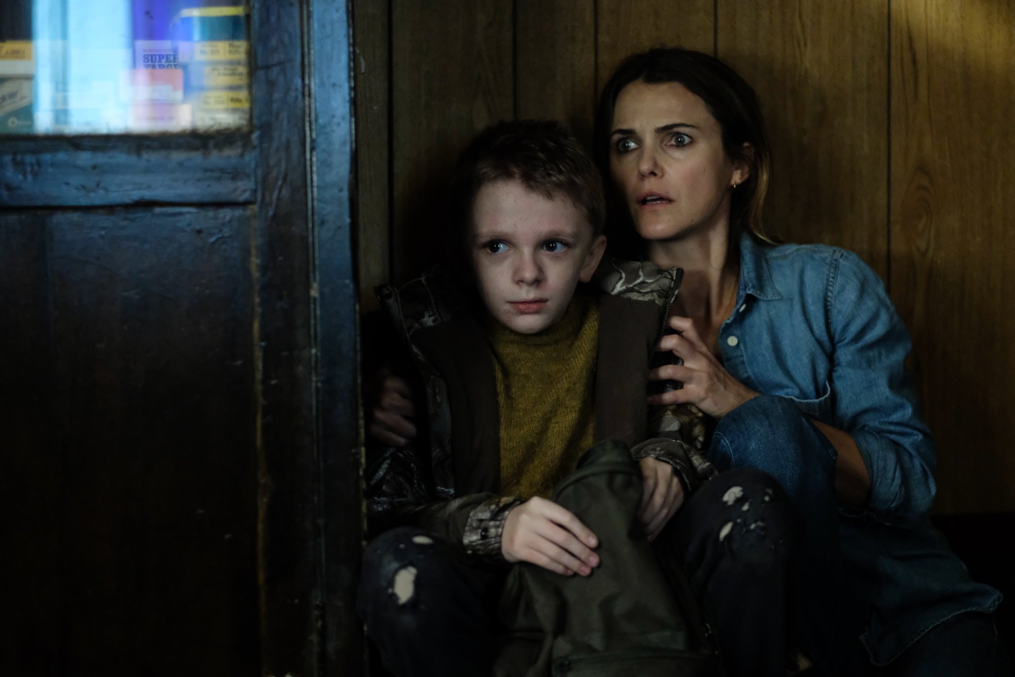 'Antlers' actors Jeremy T. Thomas and Keri Russell looking scared hiding behind furniture